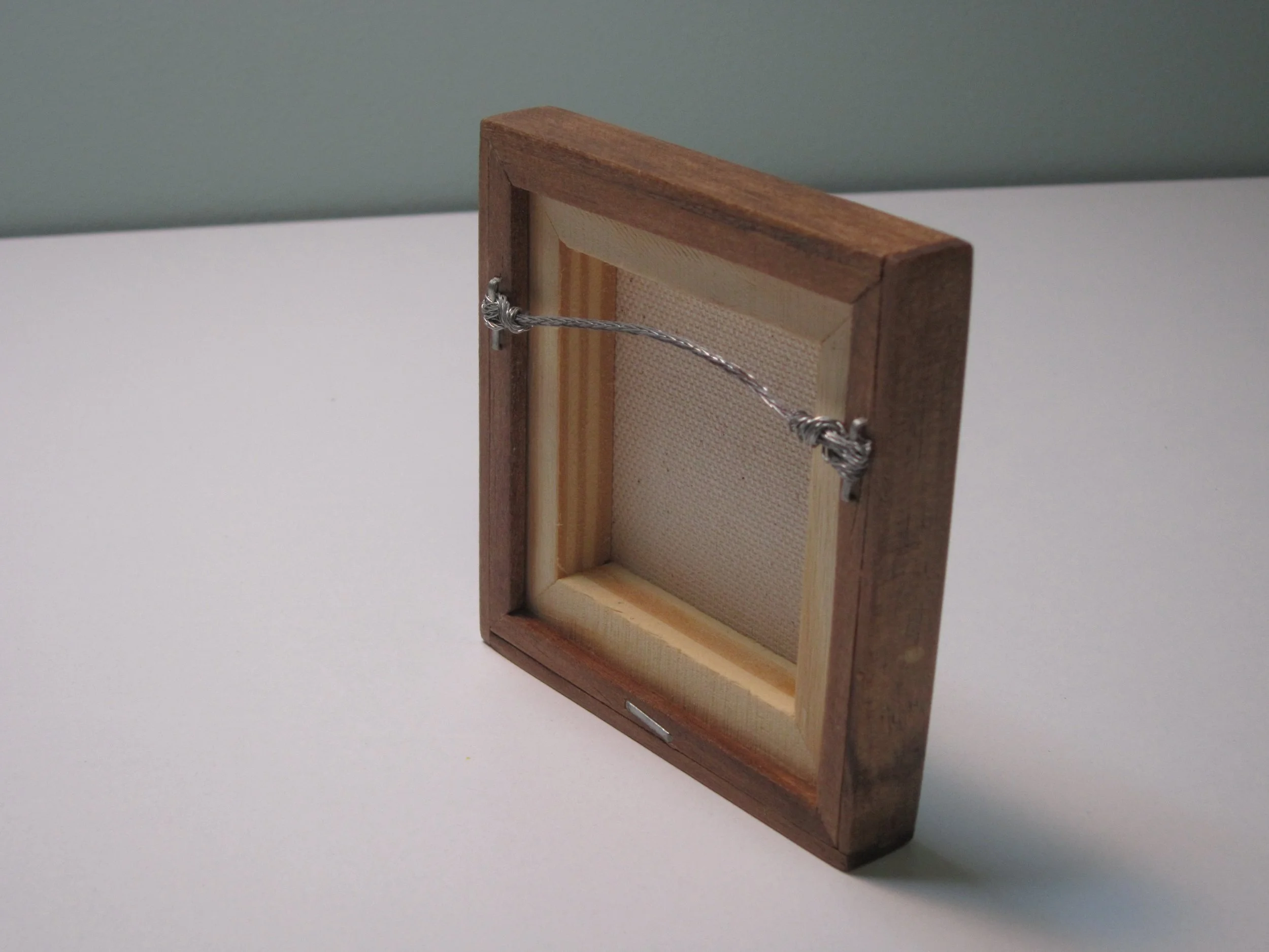 The back view of a mini canvas painting with a wood frame.