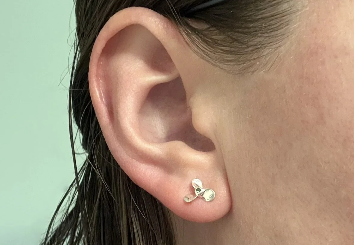 The green starboard sterling silver propeller earring on a model.