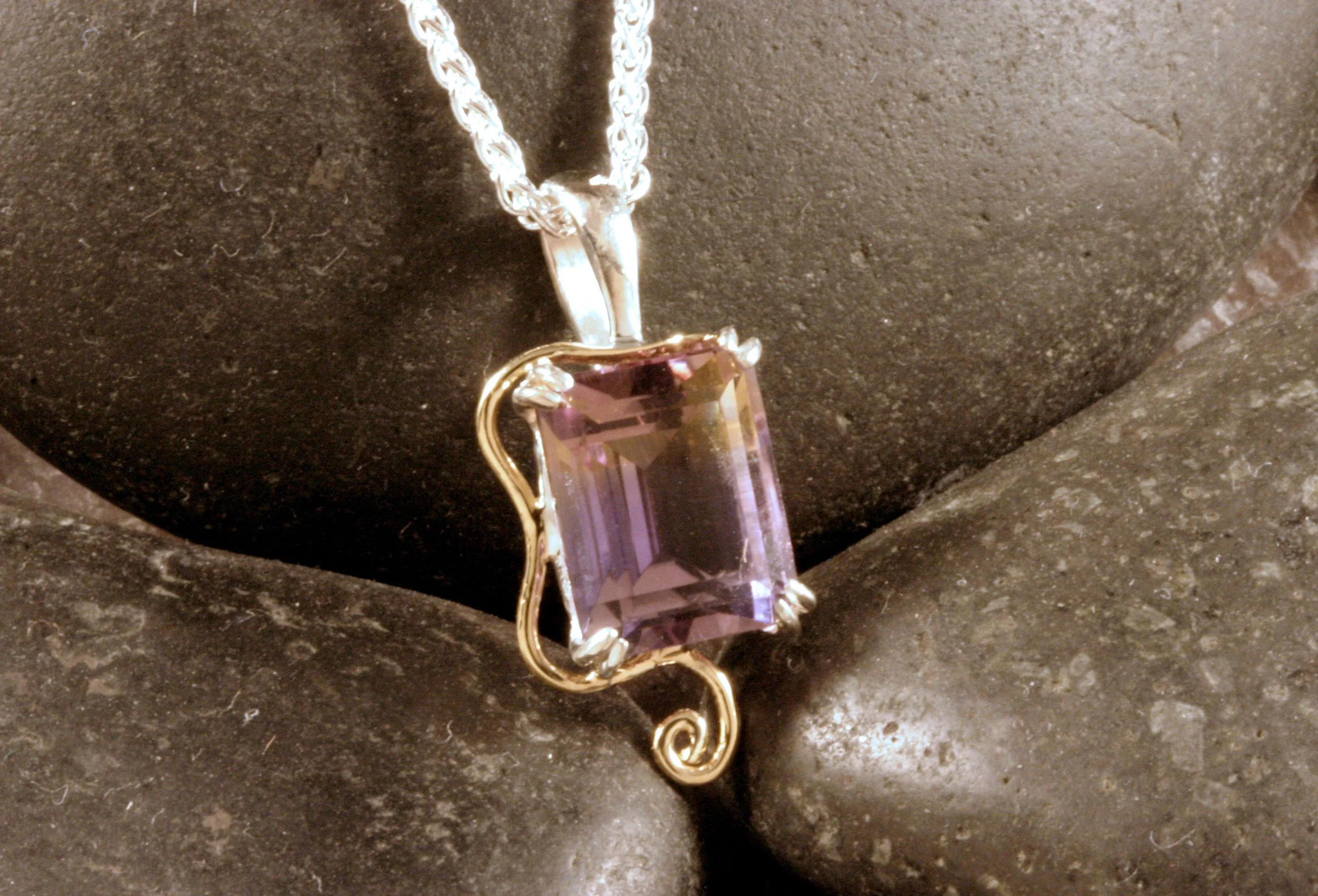 A front view of a sterling silver & 14K gold ametrine pendant with a wavy swirl design accent.