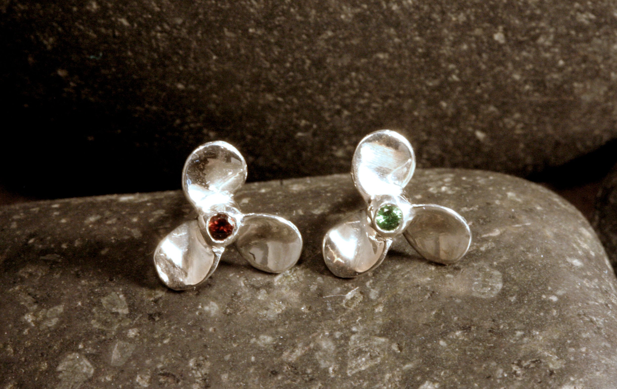 Sterling silver stud earrings of mini propellers with a red mozambique garnet for port (left) and a green tsavorite garnet for starboard (right).