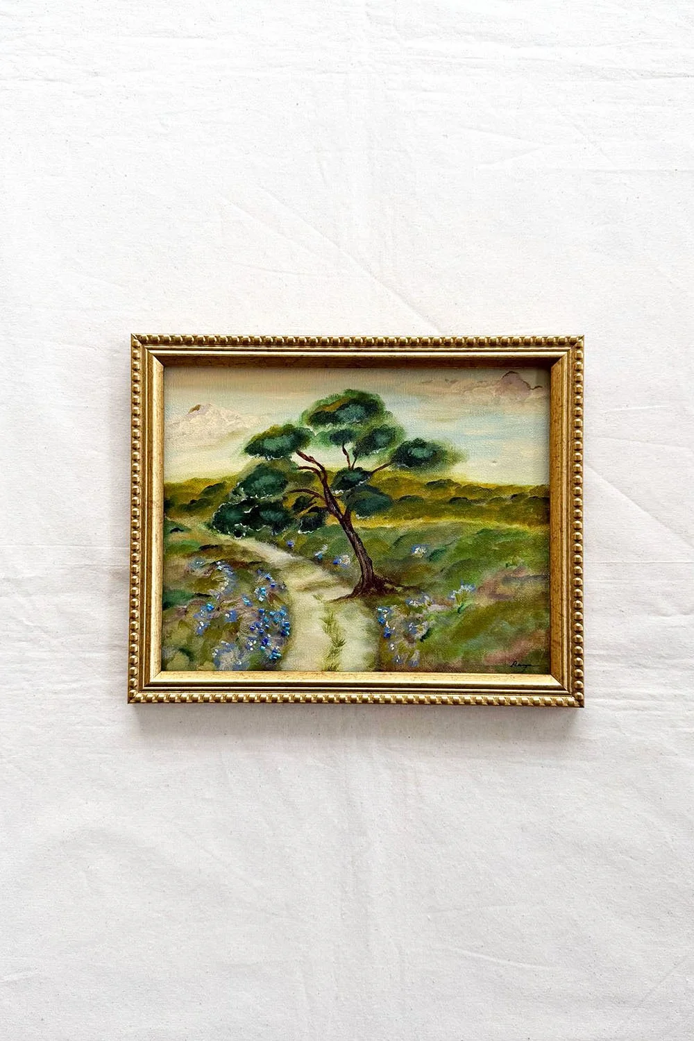 An acrylic landscape painting of a winding dirt path through rolling green hills under a soft sky, featuring a central leaning tree and shimmering glass bead textures in the foreground.