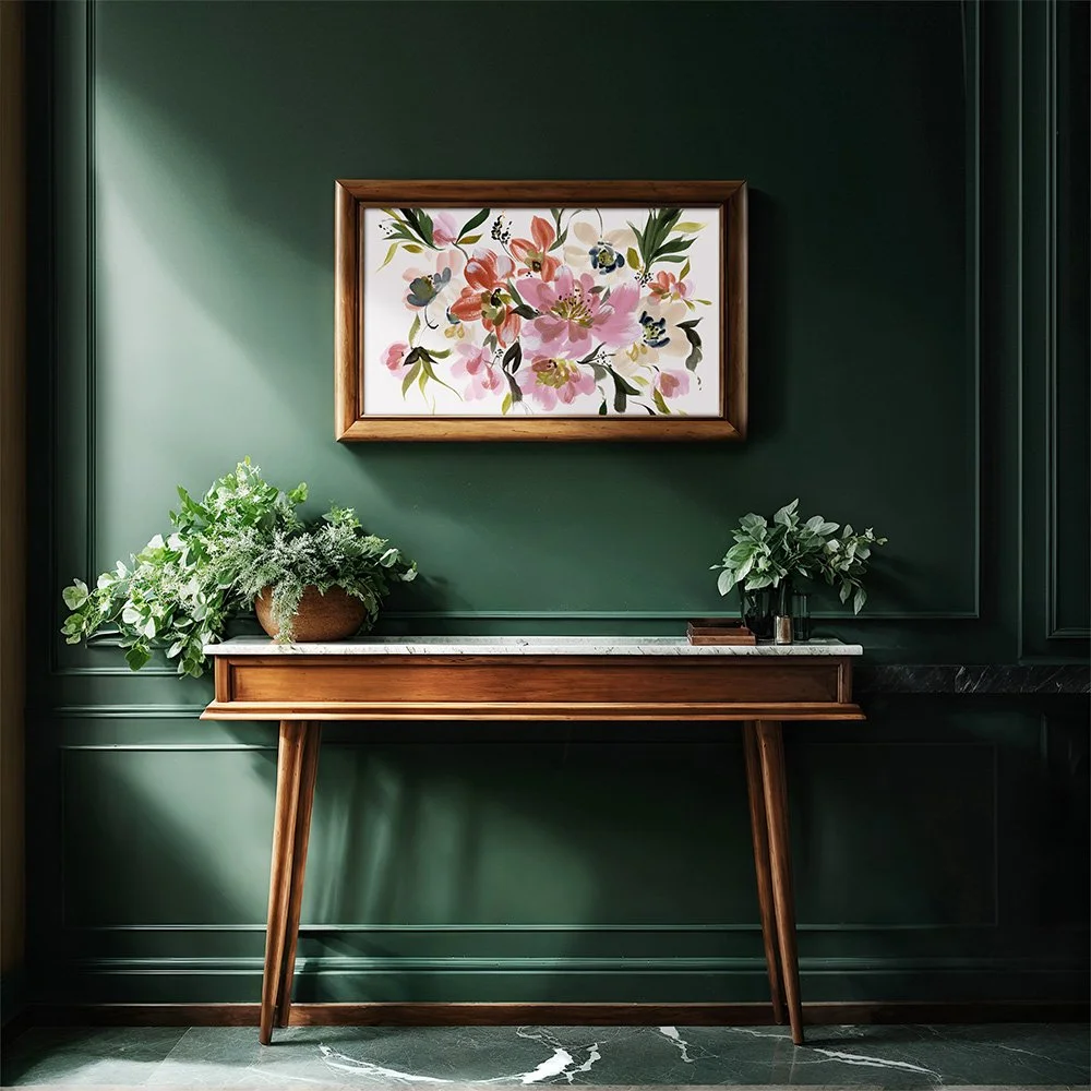 Framed botanical watercolor art with layered fall leaves underneath, set on a white surface with artist tools—highlighting the beauty of floral elegance and artisanal craftsmanship