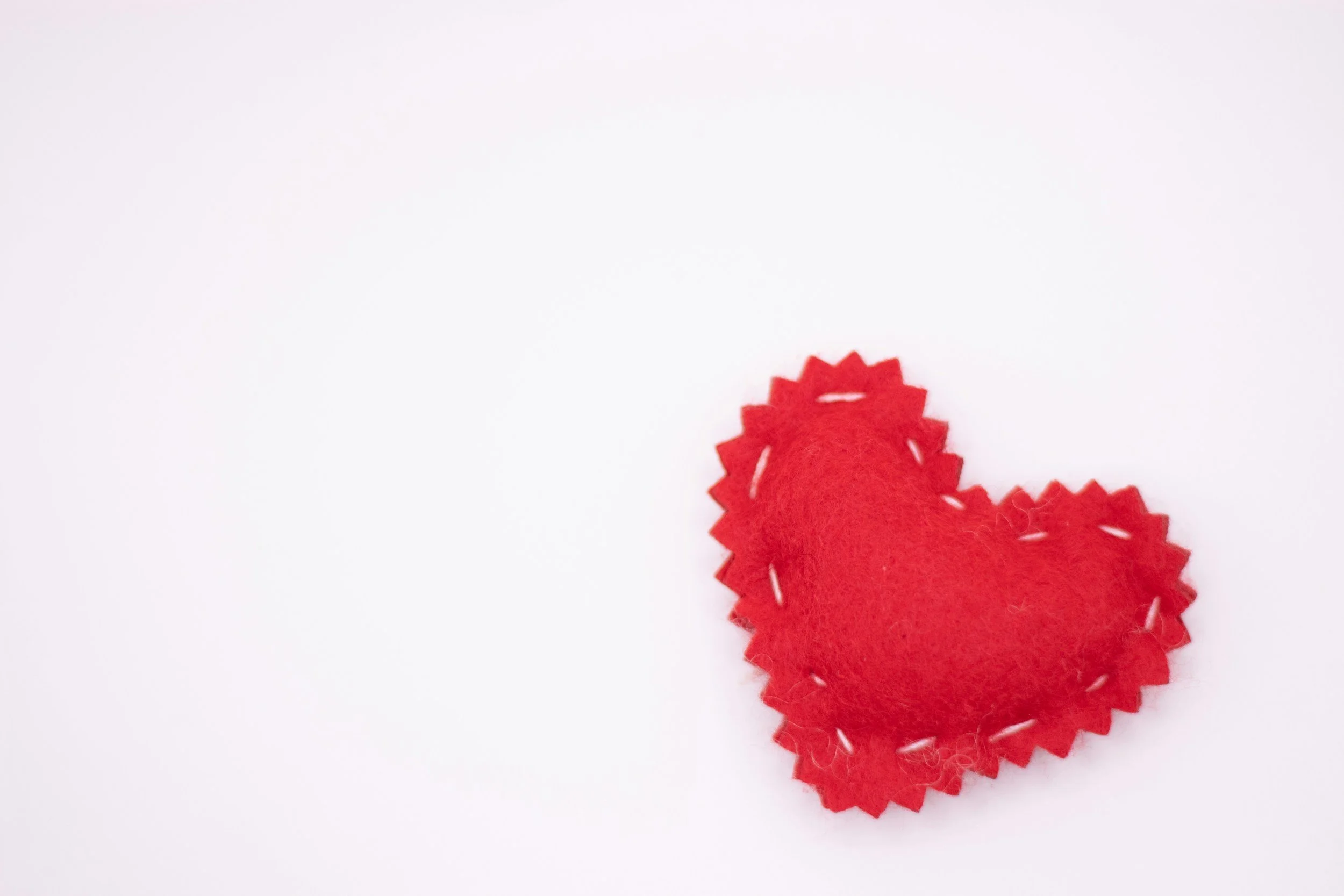 Red felt heart with zigzag edges on a white background.