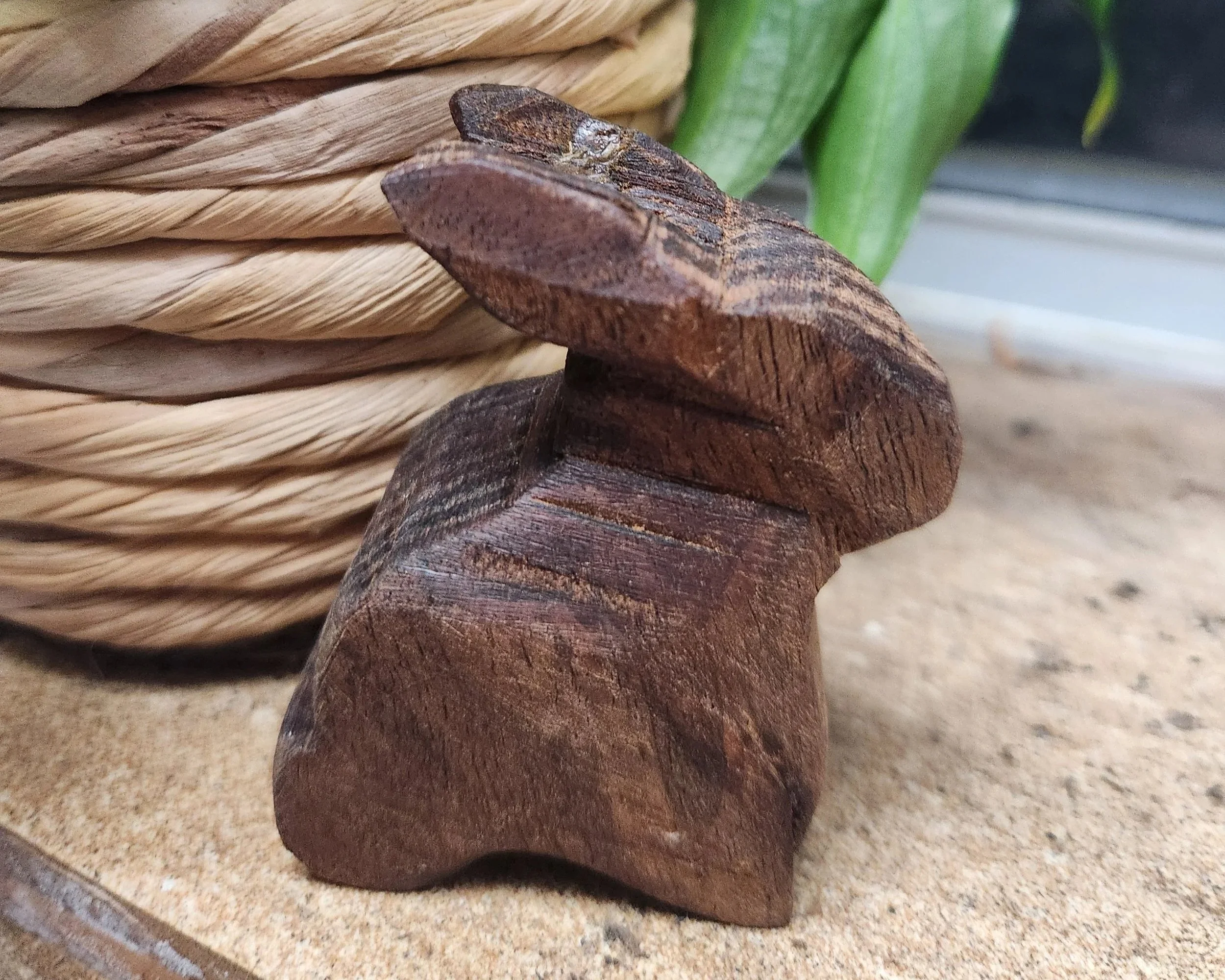 Close-up of wooden and palm leaf objects with a green plant stem in the background.