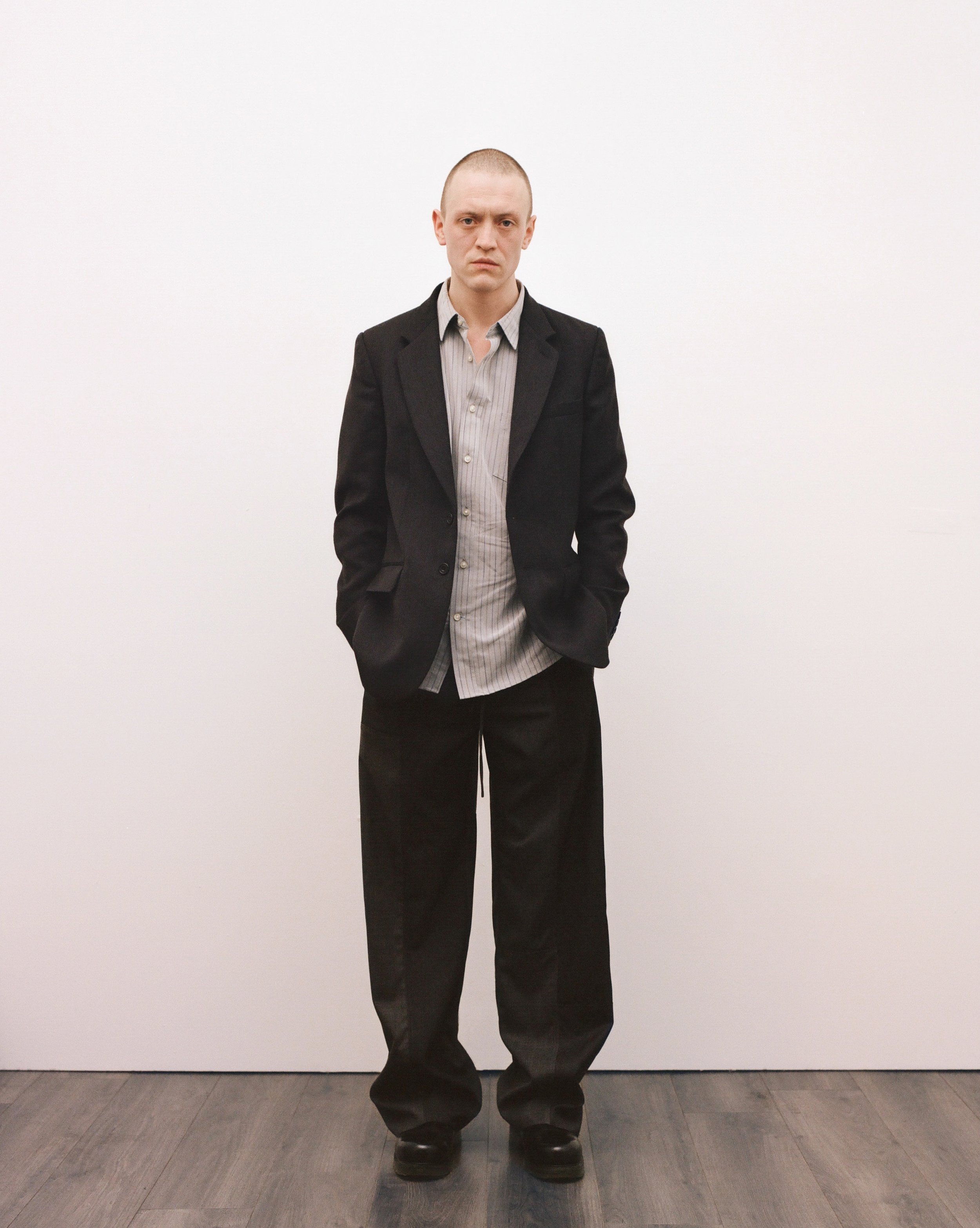 Look 5. Tom wears the Up-cycled Unisex Baggy Trousers with Collection 06 Unisex Tailored Jacket, crafted from responsibly sourced wool and repurposed suit trousers sourced from Cancer Research and The Children’s Hospice Totnes