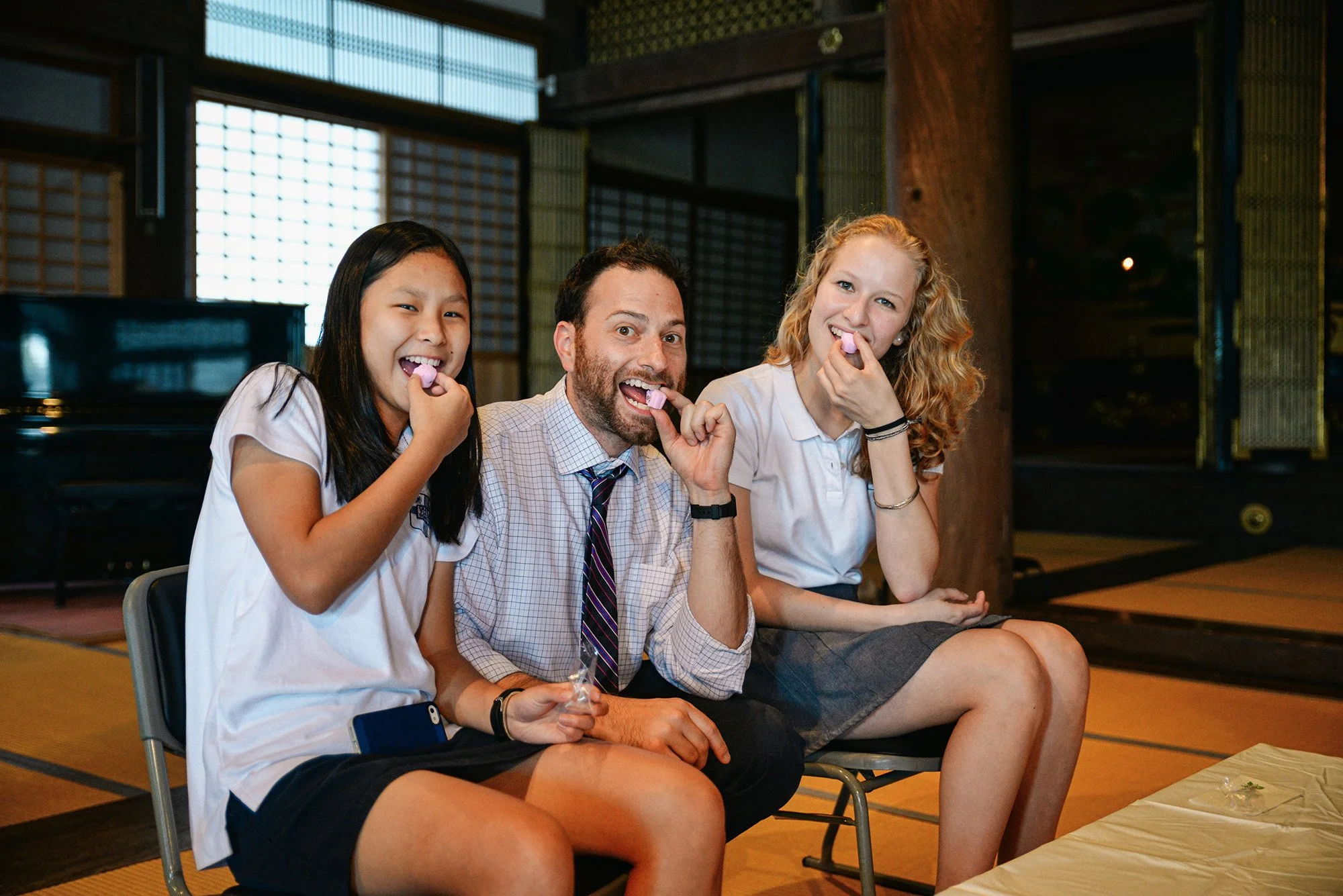 American students and teacher biting a sweet in a temple in Japan