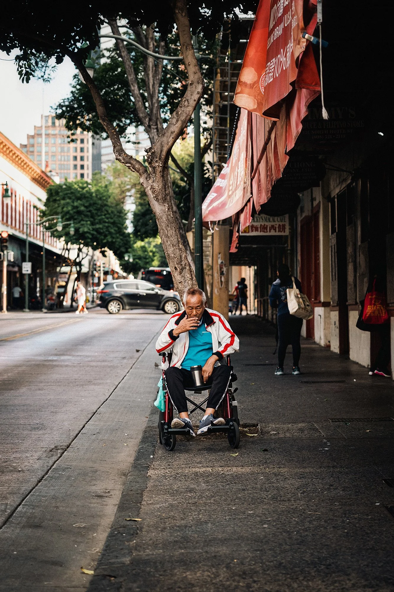 A man in a wheelchair smoking a cigarette in Chinatown, Honolulu