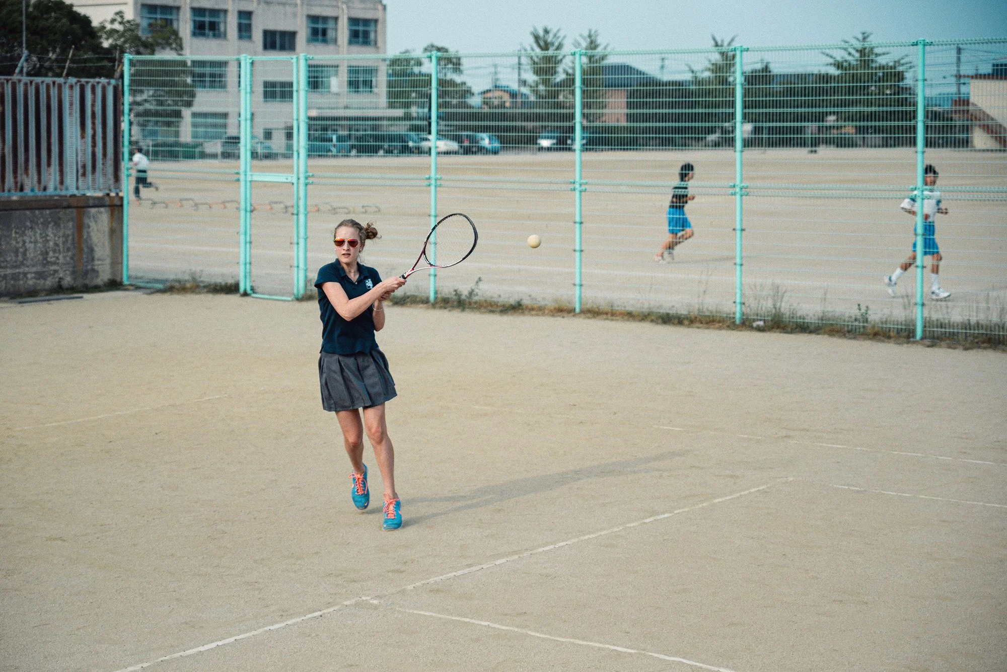American student playing soft tennis at a school in Japan