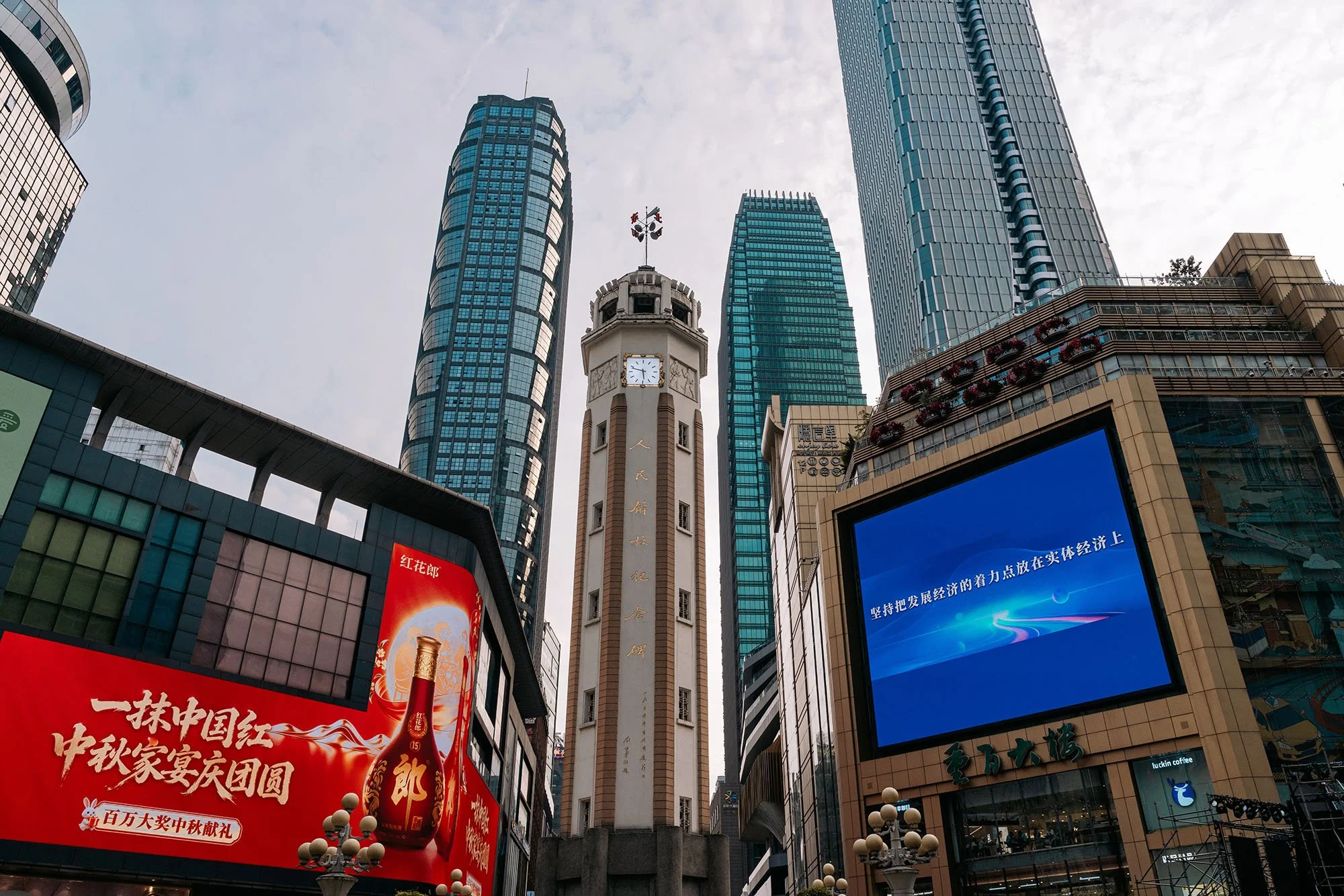 a tower monument in between buildings with skyscrapers in the background in chongqing china