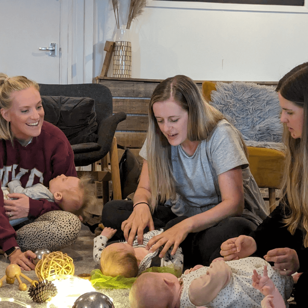 Three women sitting on the floor with babies, interacting and engaging in a play session at The Nest in Truro, while the new mums talk about their postnatal experiences.