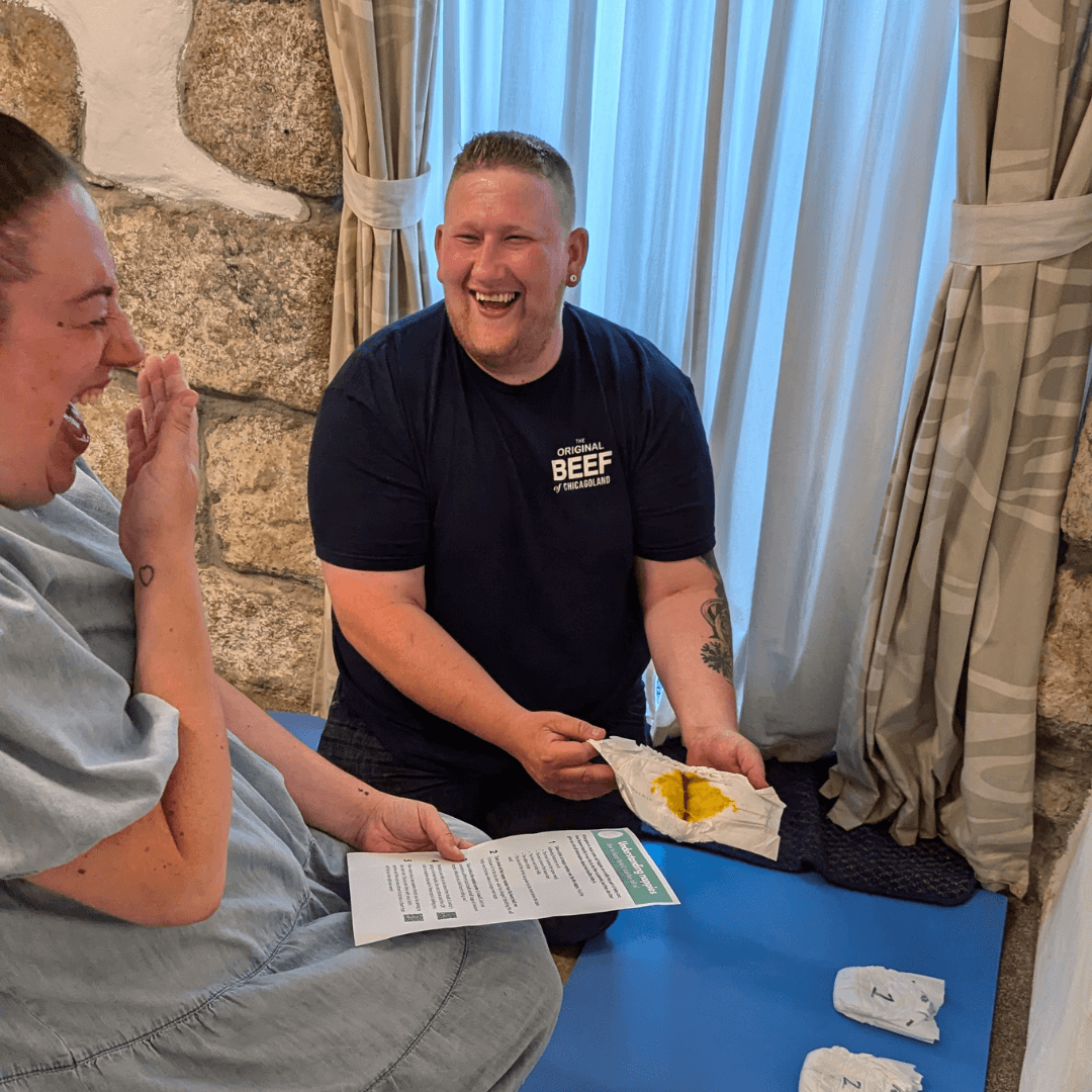 A pregnant woman and her partner laugh as they learn about newborn nappies at their group antenatal class in Truro, Cornwall