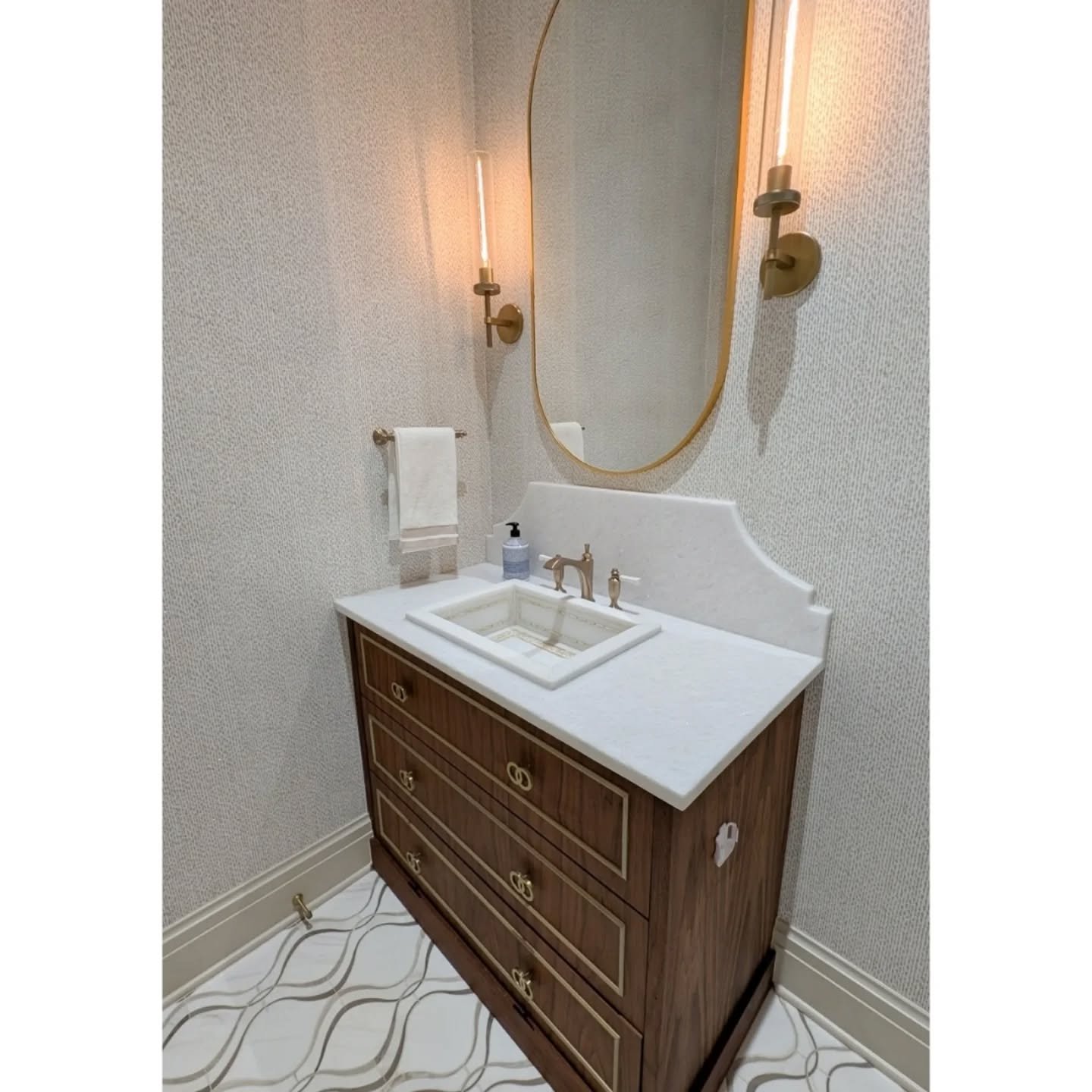 One of our top powder room designs, featuring beautiful marble floors and a custom dark stained walnut vanity with gold-painted moulding and a curved marble backsplash. 

#interiorsbybethreed #powderroomdesign