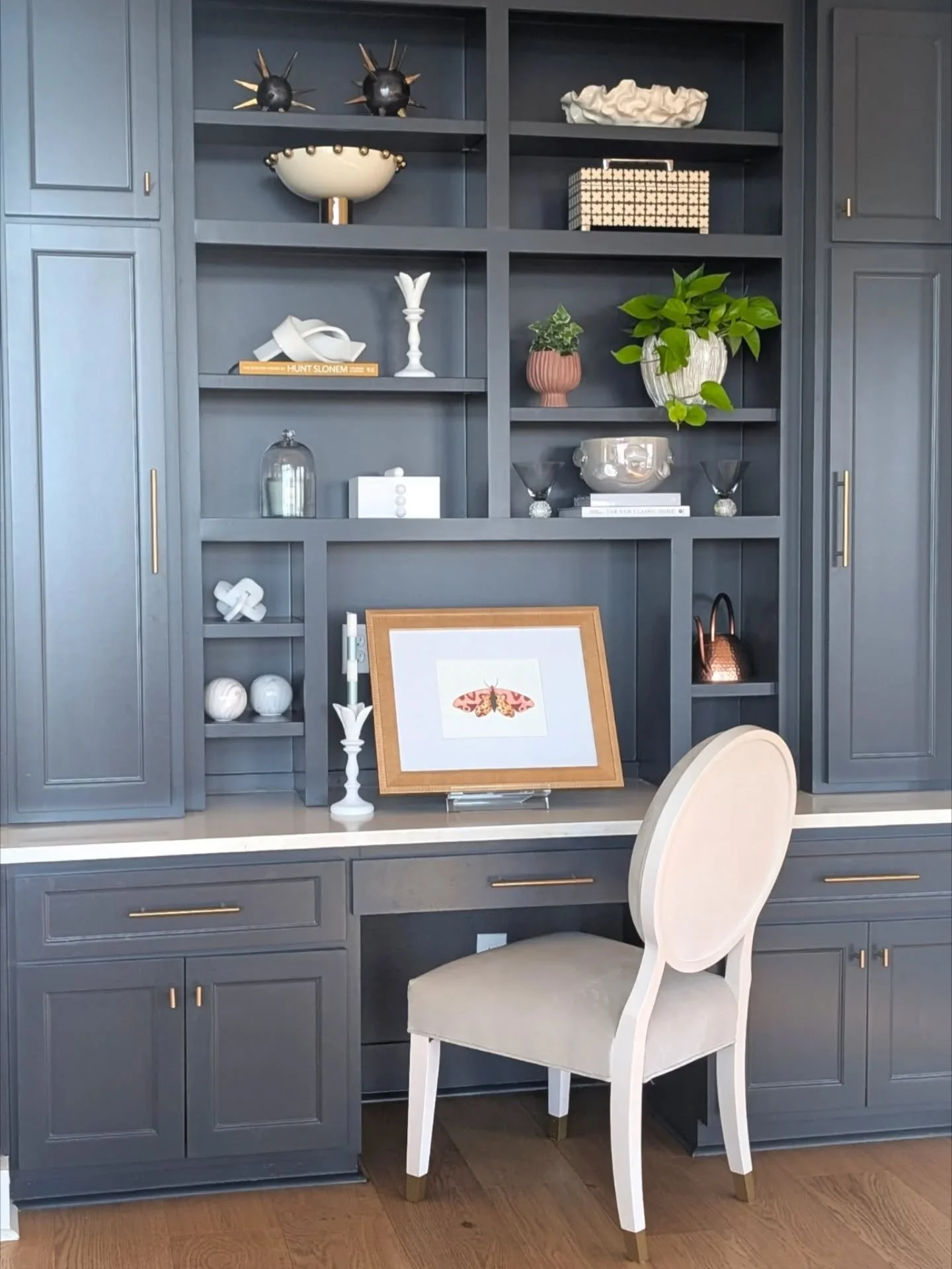 This bookshelf is finally having its moment! ↪️ We like to use objects with different textures such as the spiked balls at the top, the striped candle stick, glass globe over the candle, checkered box and live plants. Even when clients say they don't