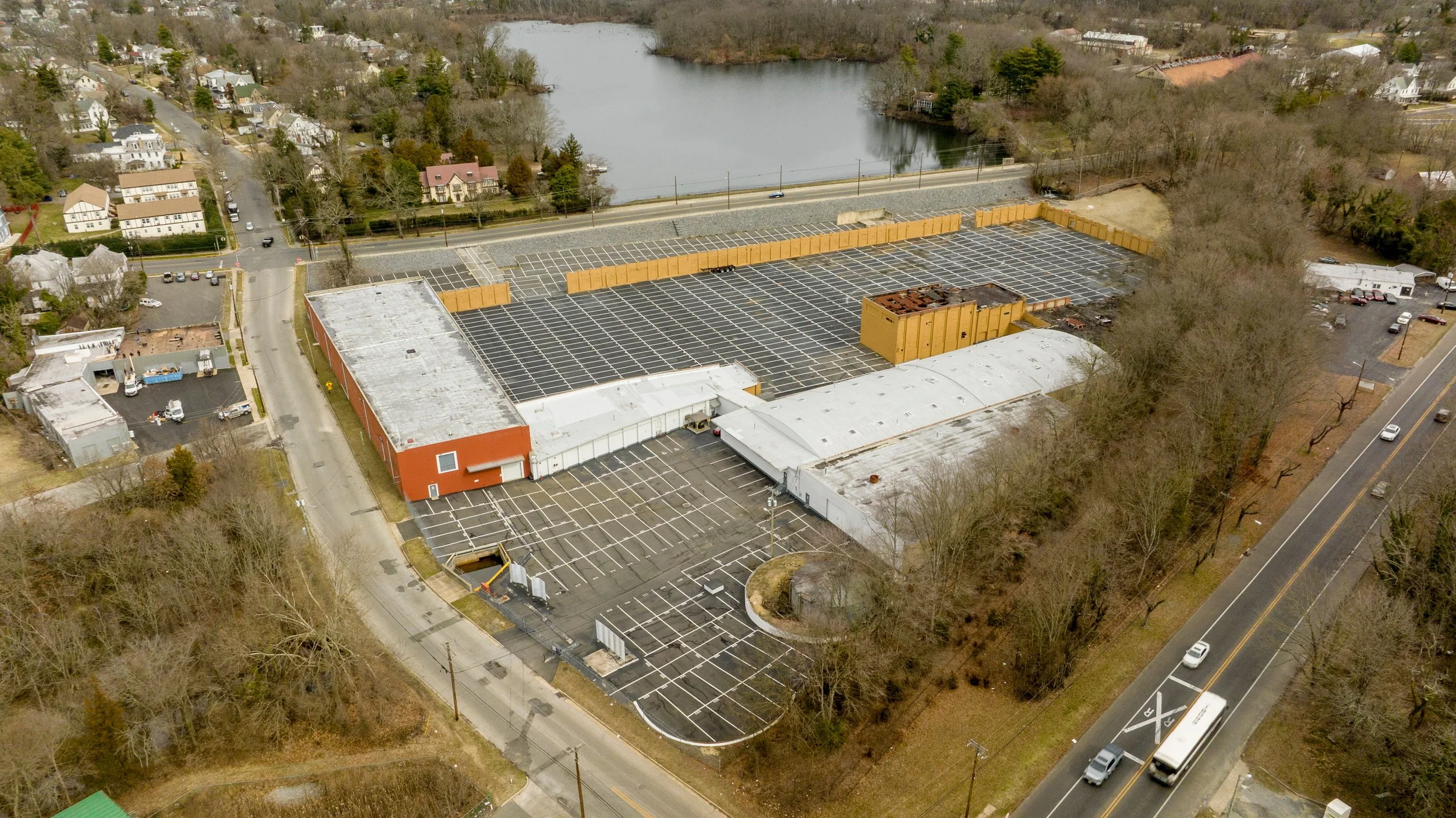An aerial photograph showing a compound in Bridgeton, New Jersey, where hundreds of used car dealers are registered. The giant parking lot is empty.