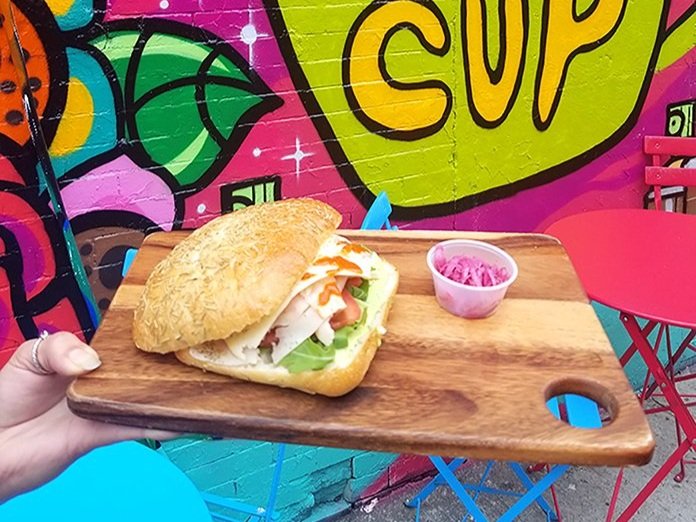 The Smoked Turkey Sandwich plated with our Pickled Onions. Mural and outdoor seating in the background.