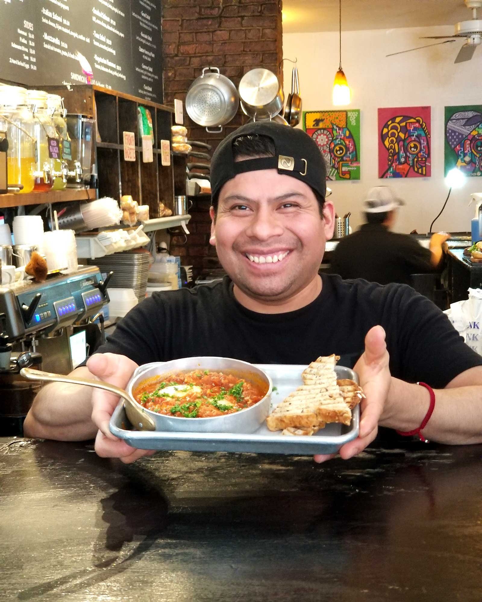 Employee presenting our Homemade Shakshuka with Whole Wheat Toast.