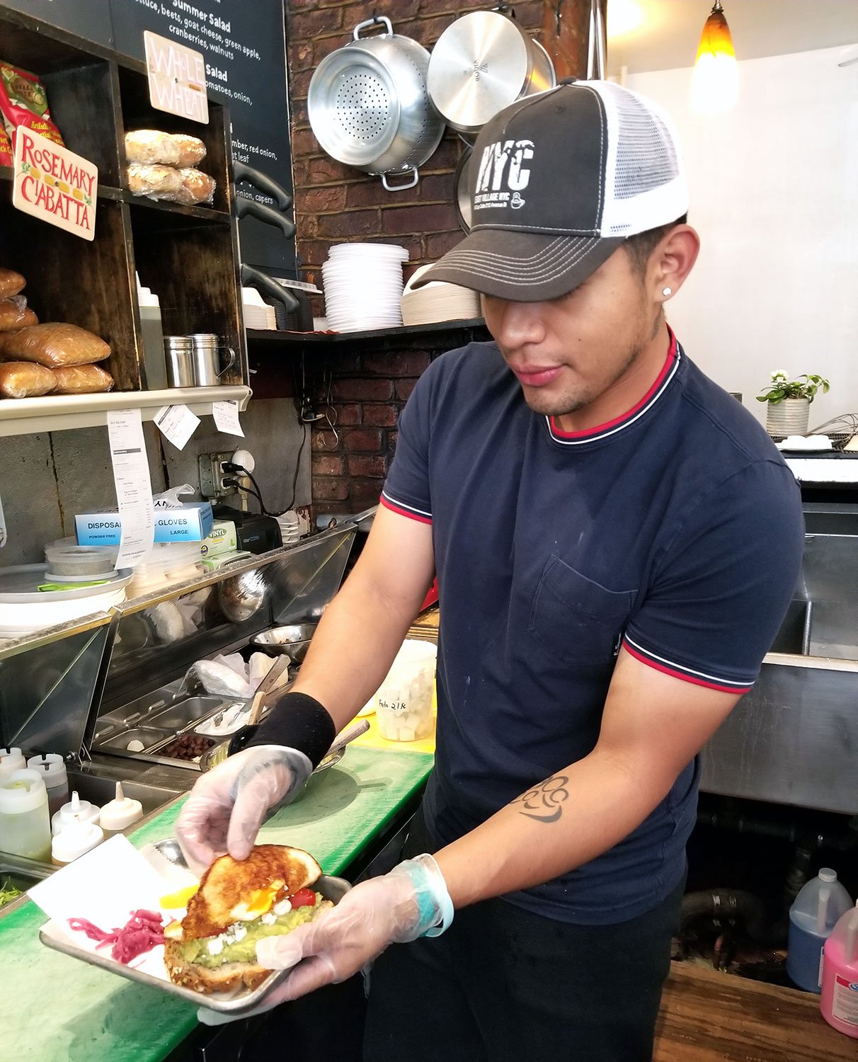 Employee adding a fried egg to our Avocado Toast.