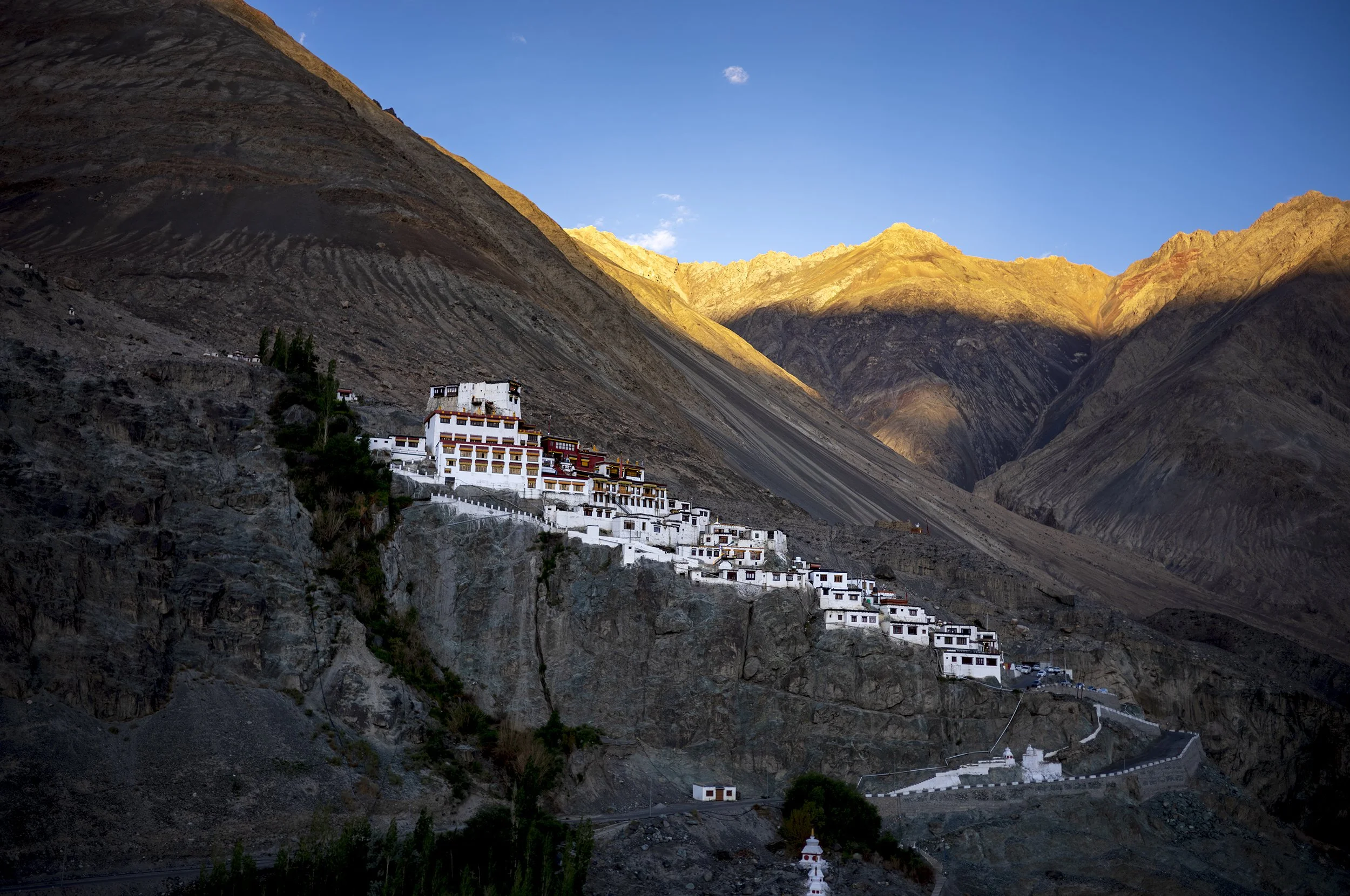 Golden early morning light spilling onto the mountains behind Diskit Monastery
