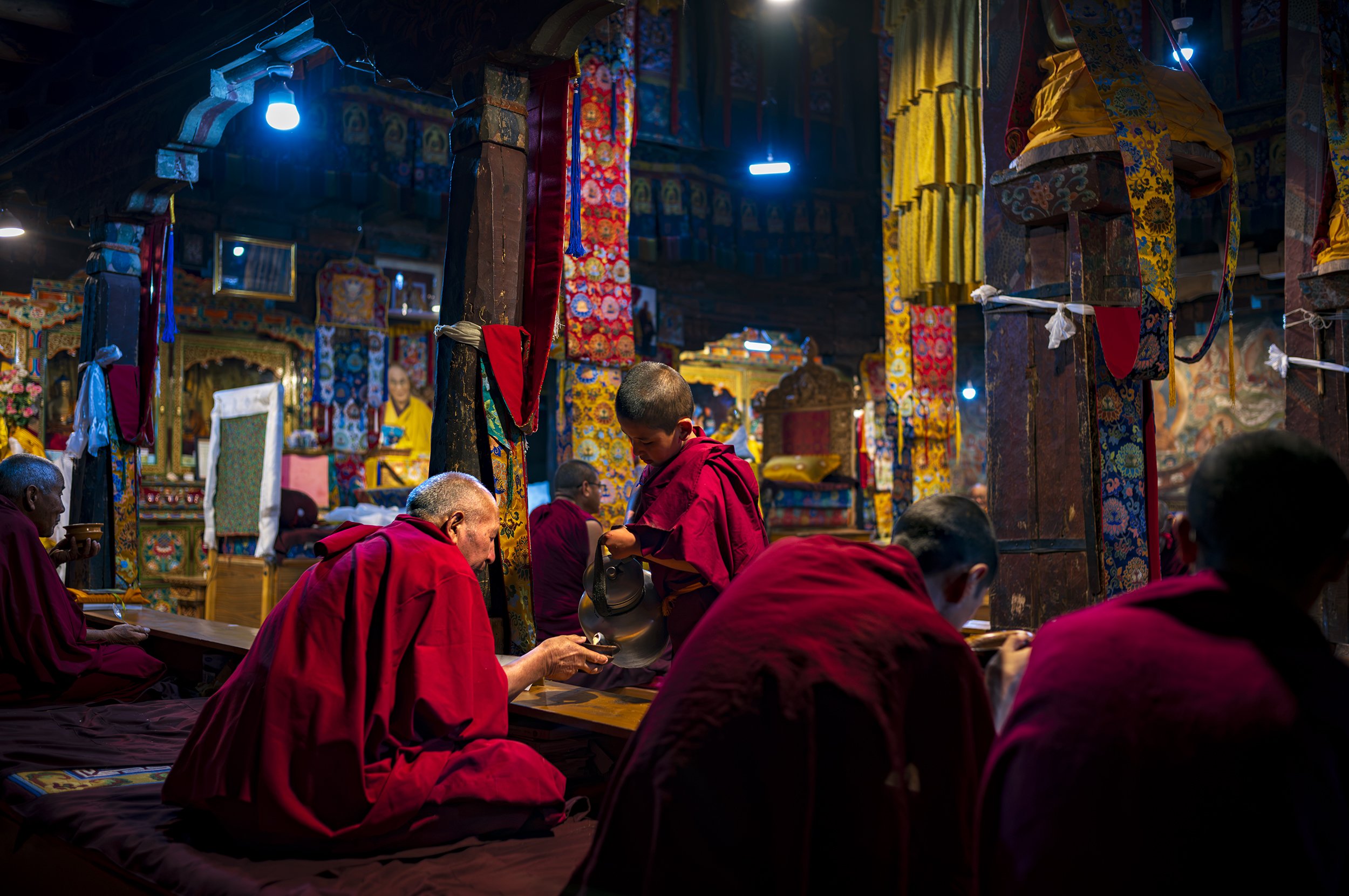 A novice Buddhist monk serves the first butter tea at daybreak prayers.  The pot is clearly very hot & heavy, but they attend to their task with practiced precision amongst the intense incense and chanting of “om mani padme hum” which translates to "