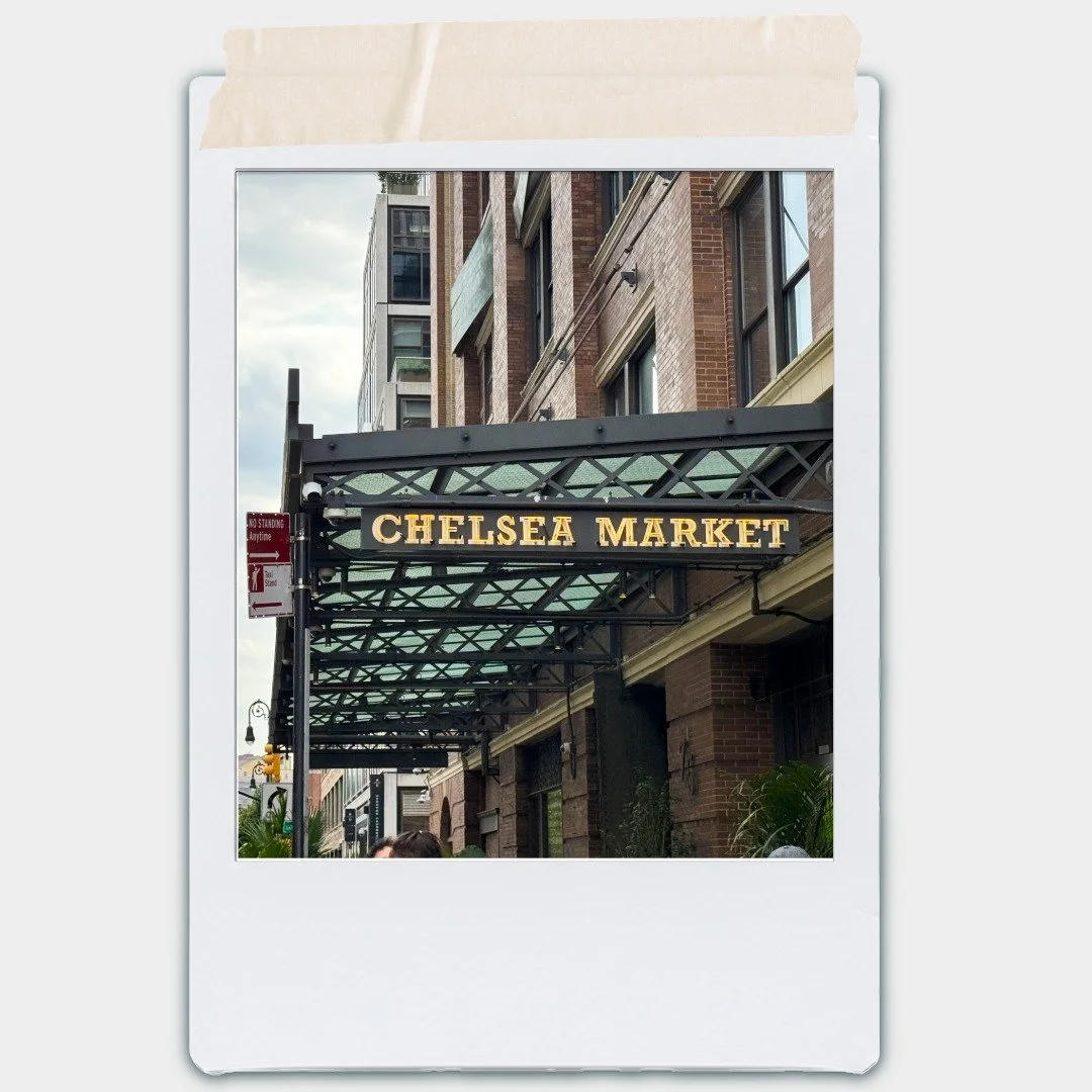 Street view of Chelsea Market entrance with a black metal awning and yellow illuminated sign.