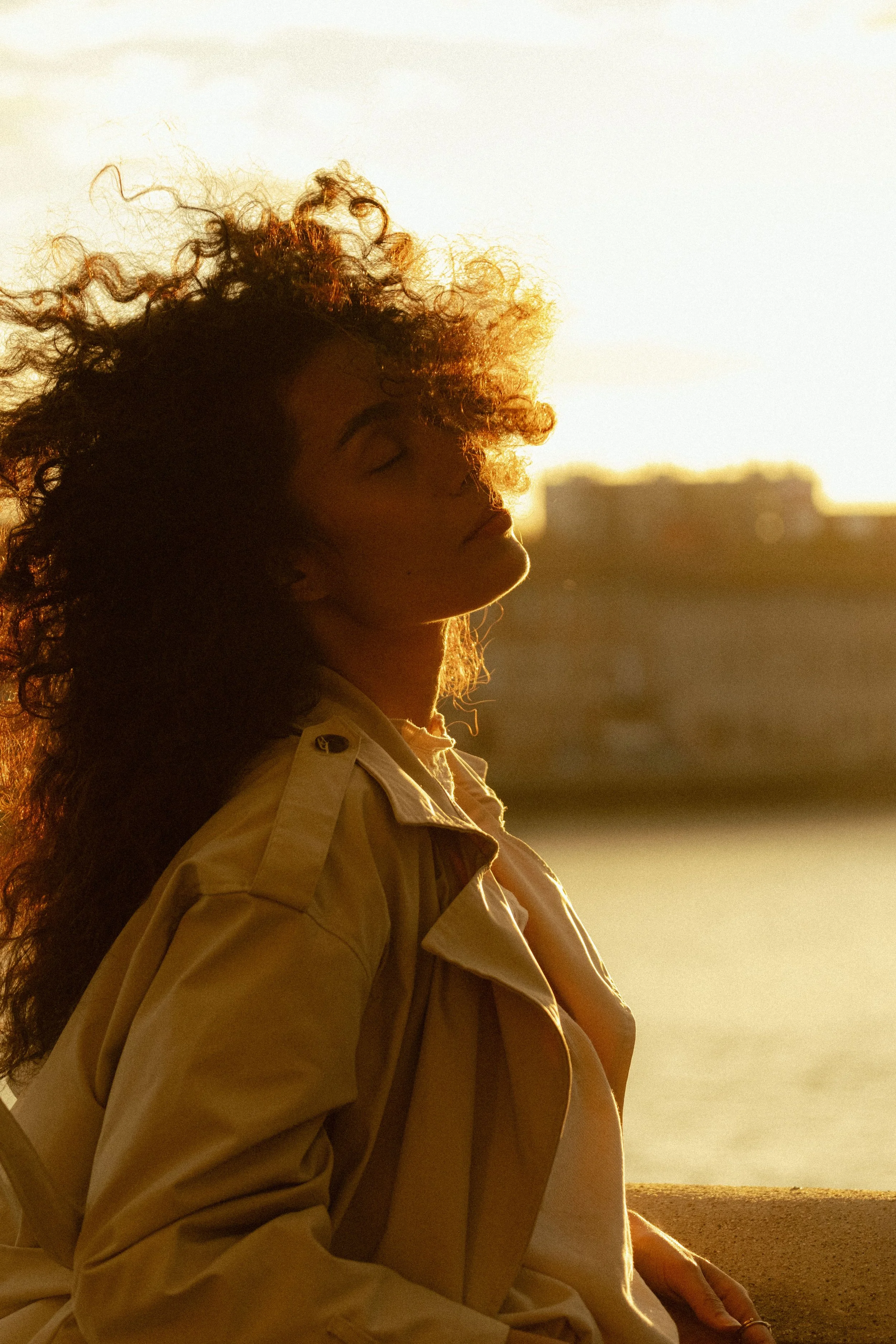 portrait dune femme en ville trench et soleil a travers ses cheveux