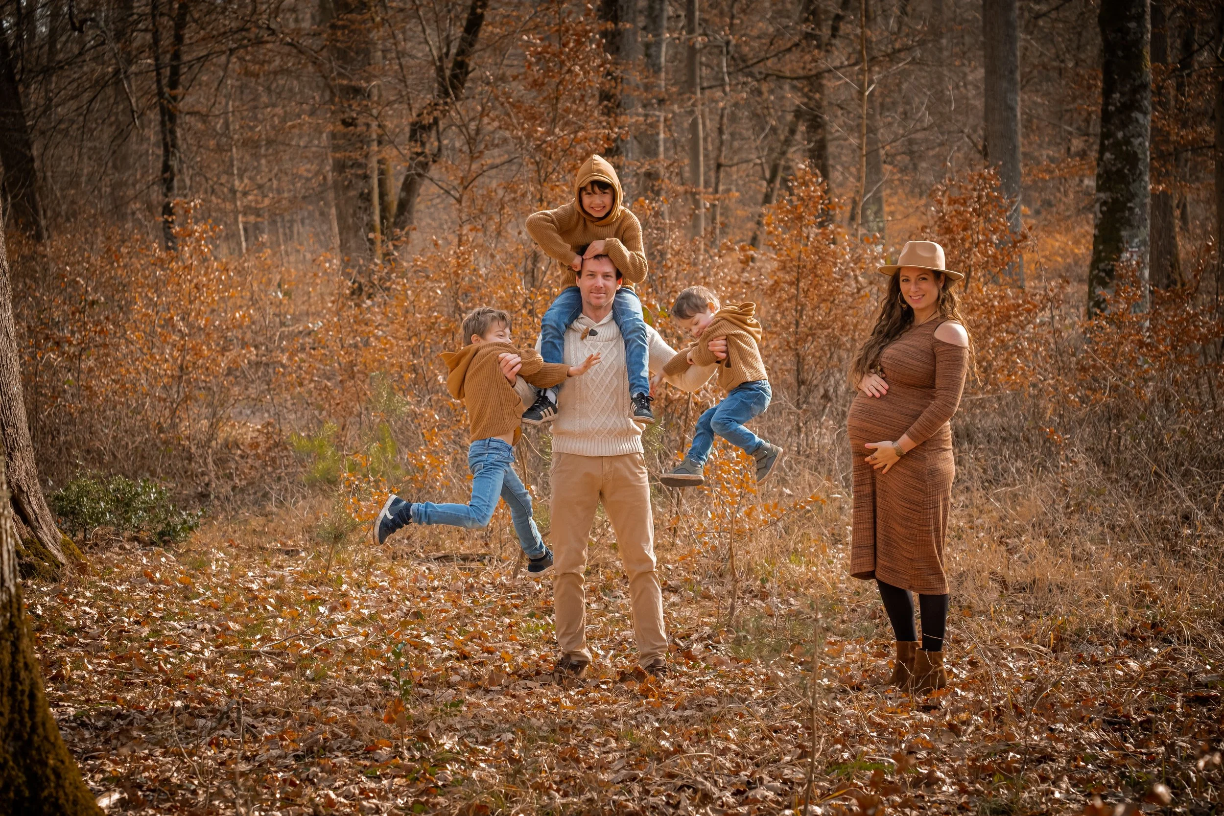 seance grossesse en famille drole avec les trois enfants accroche a leur père