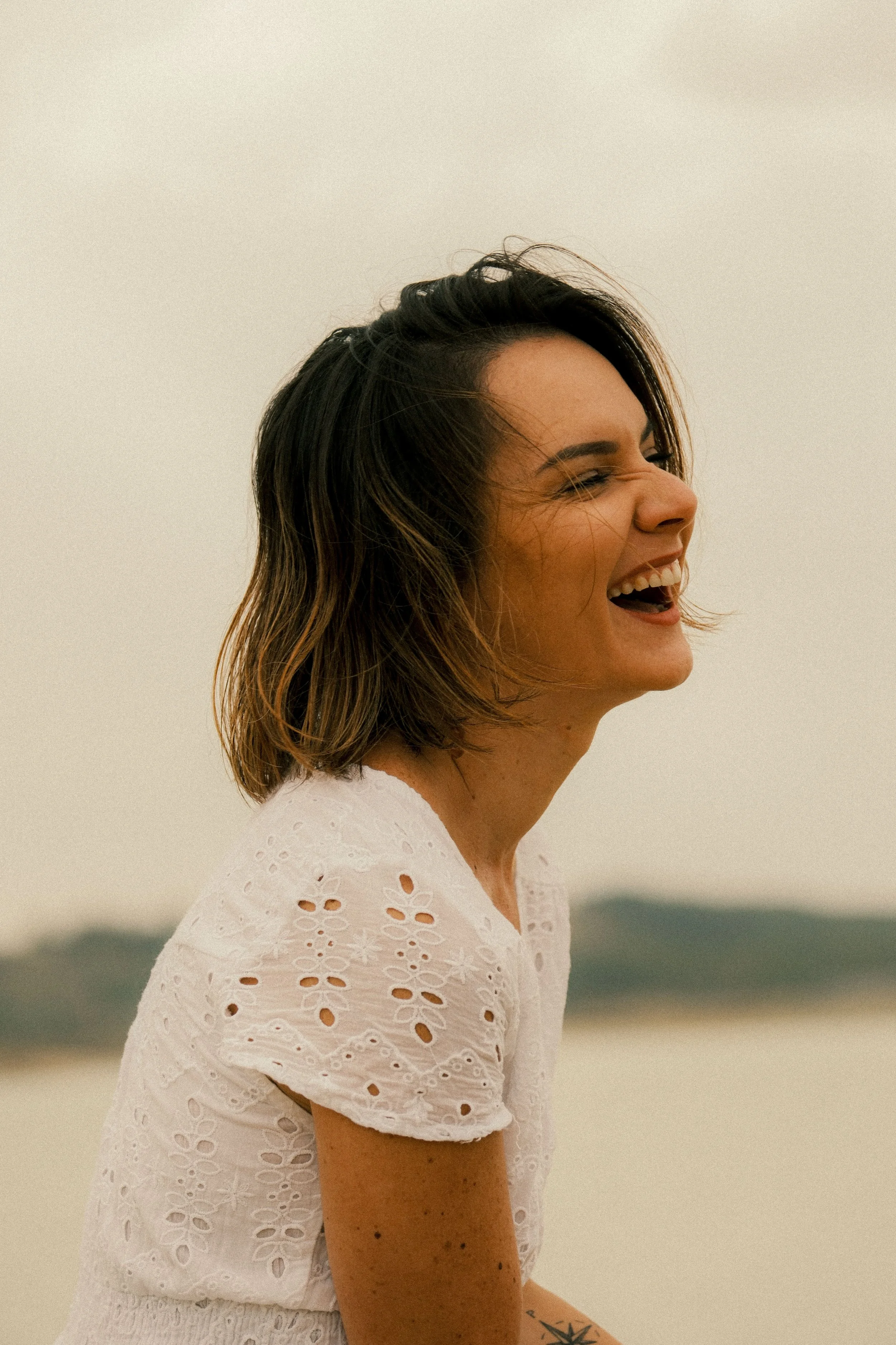 femme qui eclate de rire en robe blanche