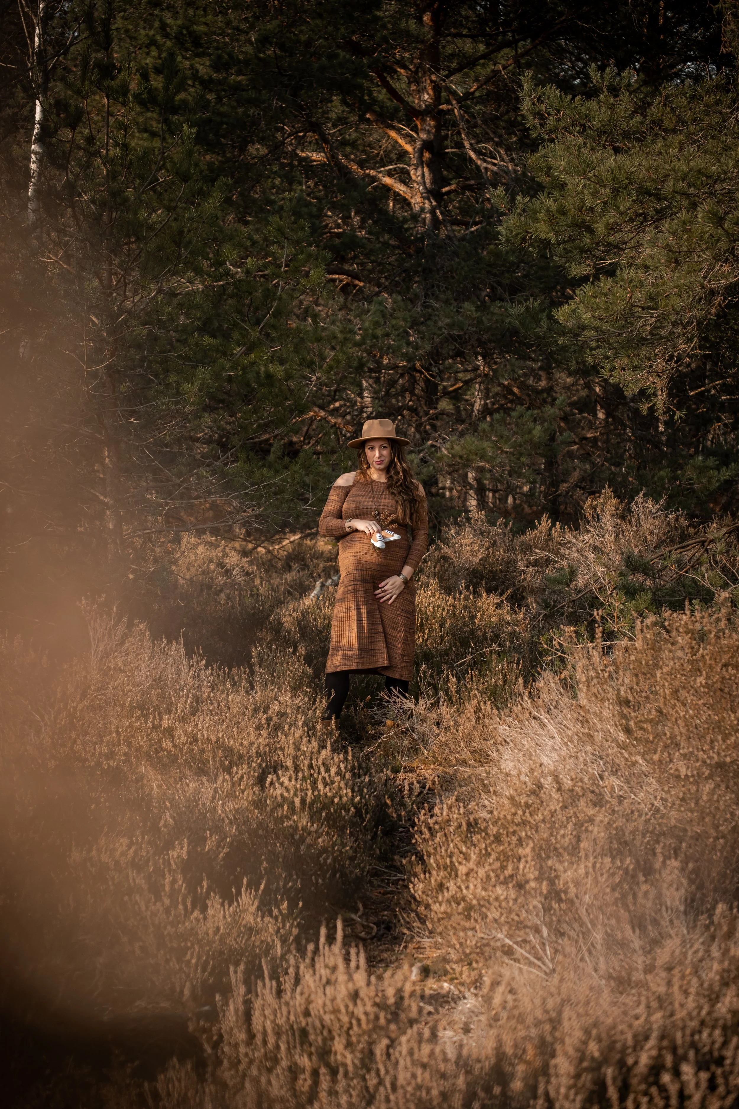 photo de la maman enceinte dans la foret avec les chaussures du futur bebe
