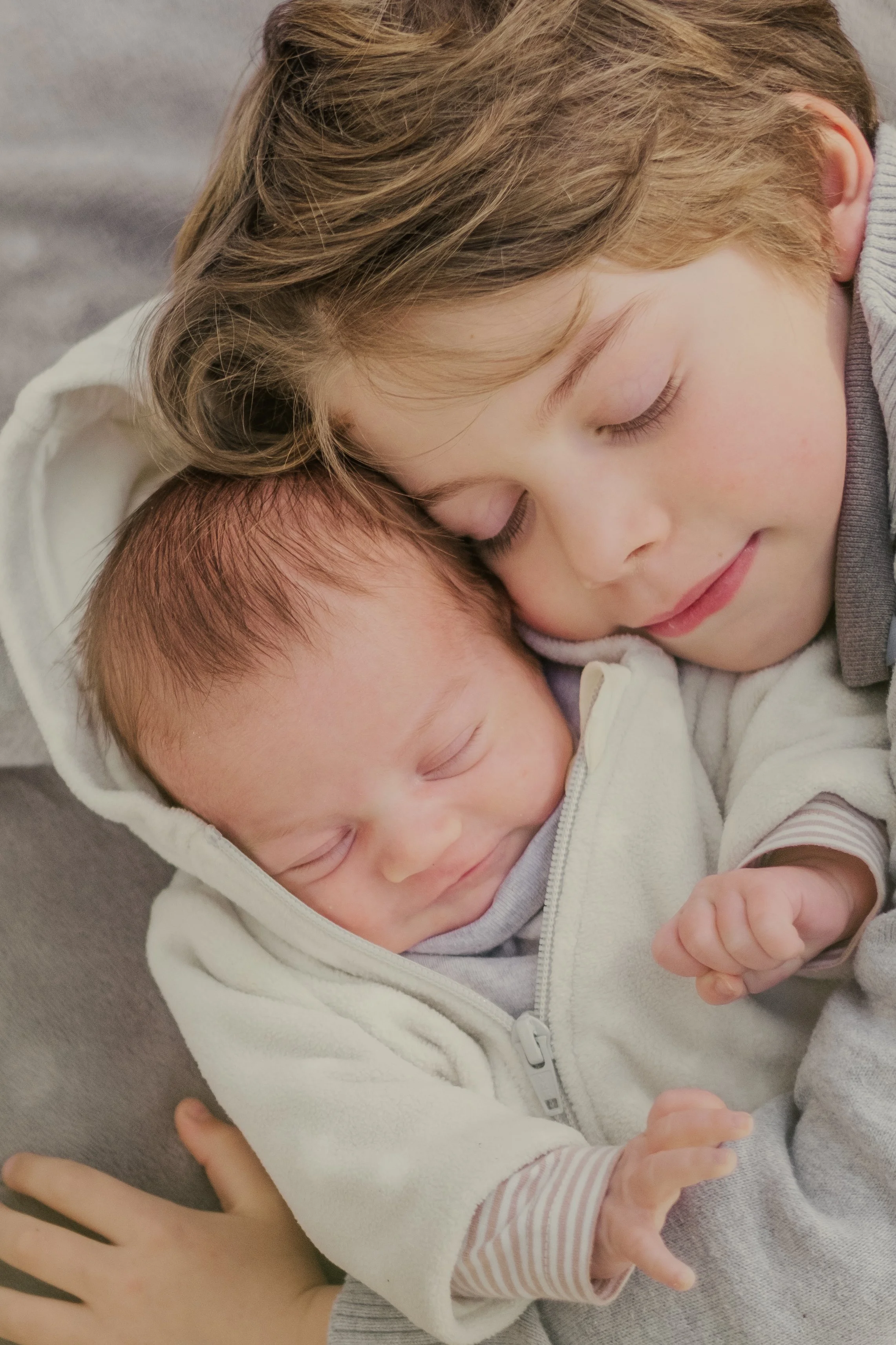 le  grand frere met sa tete contre celle du nouveau ne et ferme les yeux