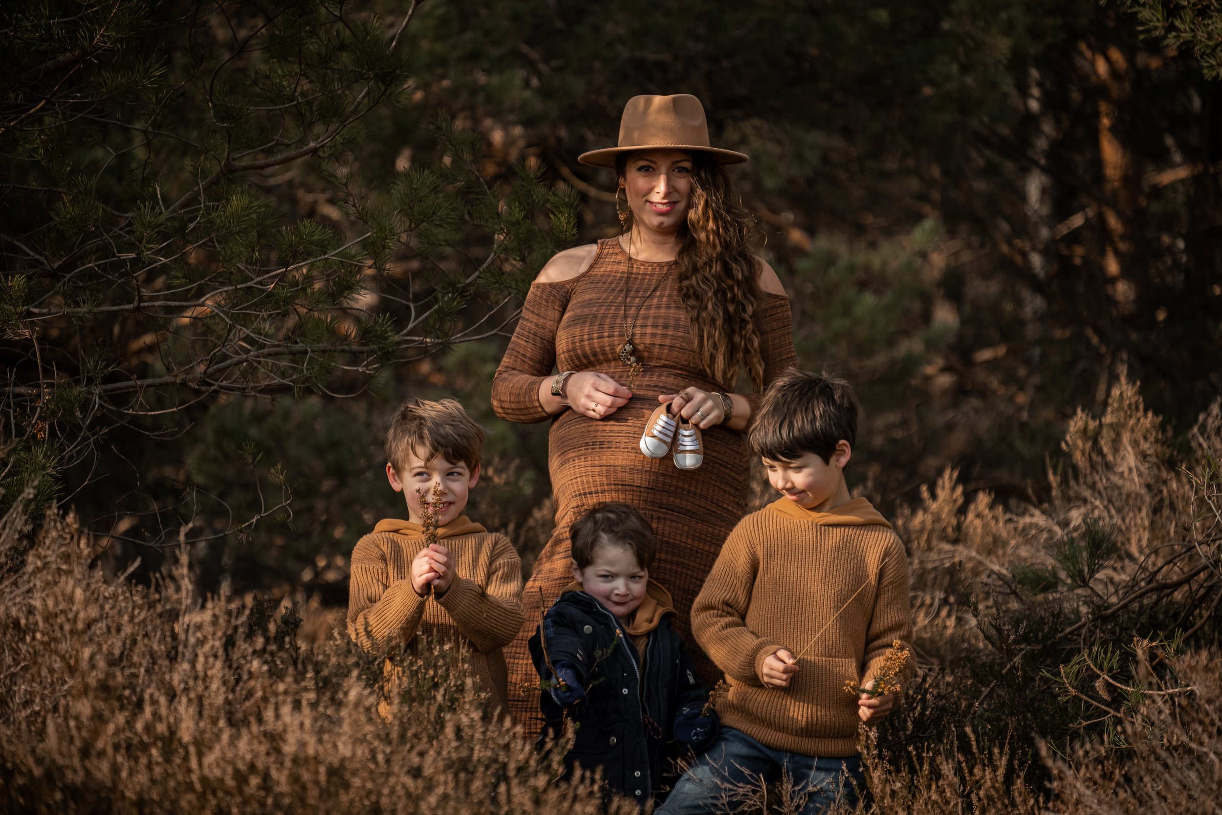 portrait des trois enfants et de la maman qui tient des petites chaussures sur son ventre de grossesse
