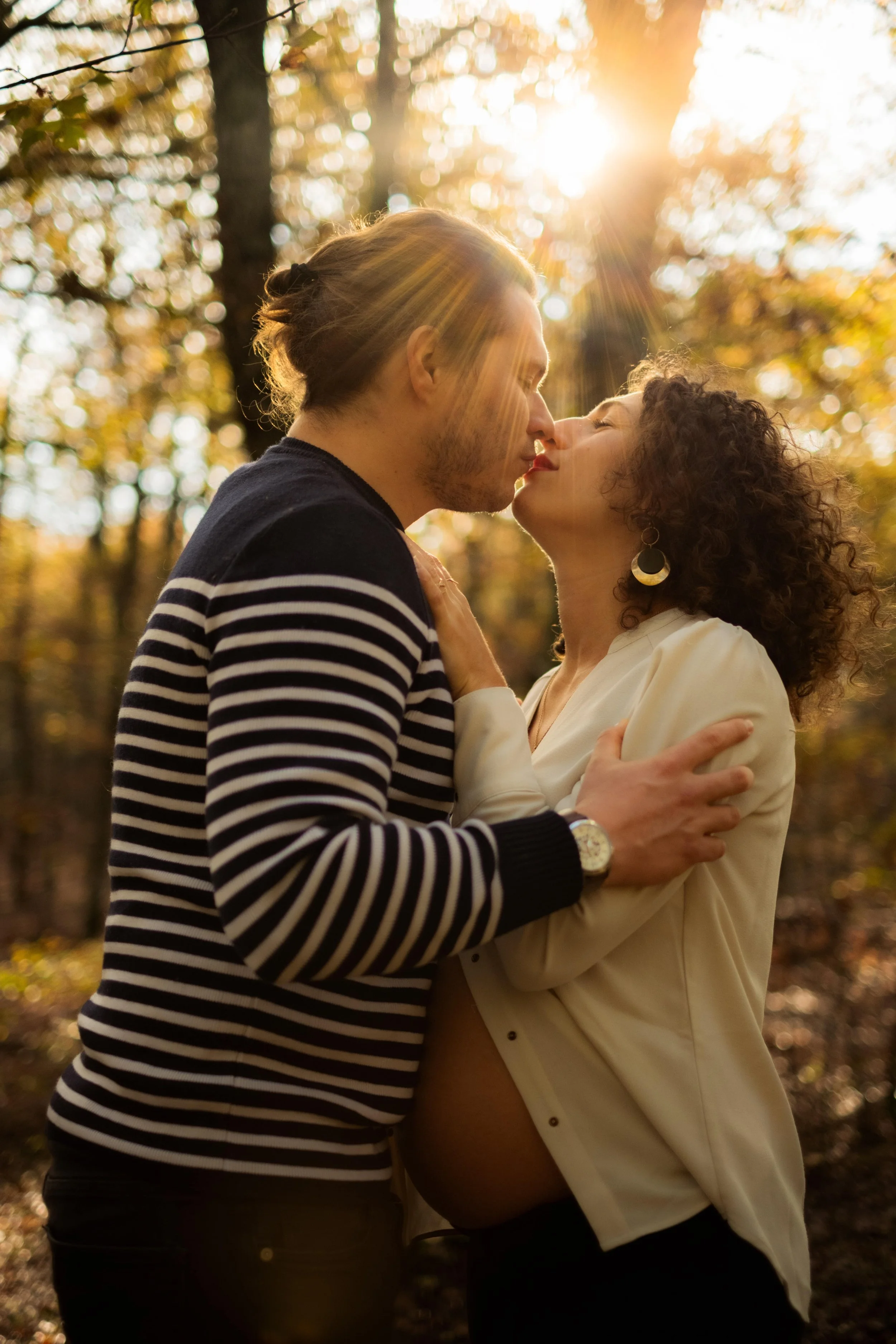 homme qui embrasse sa femme enceinte le soleil passe à travers le feuillage
