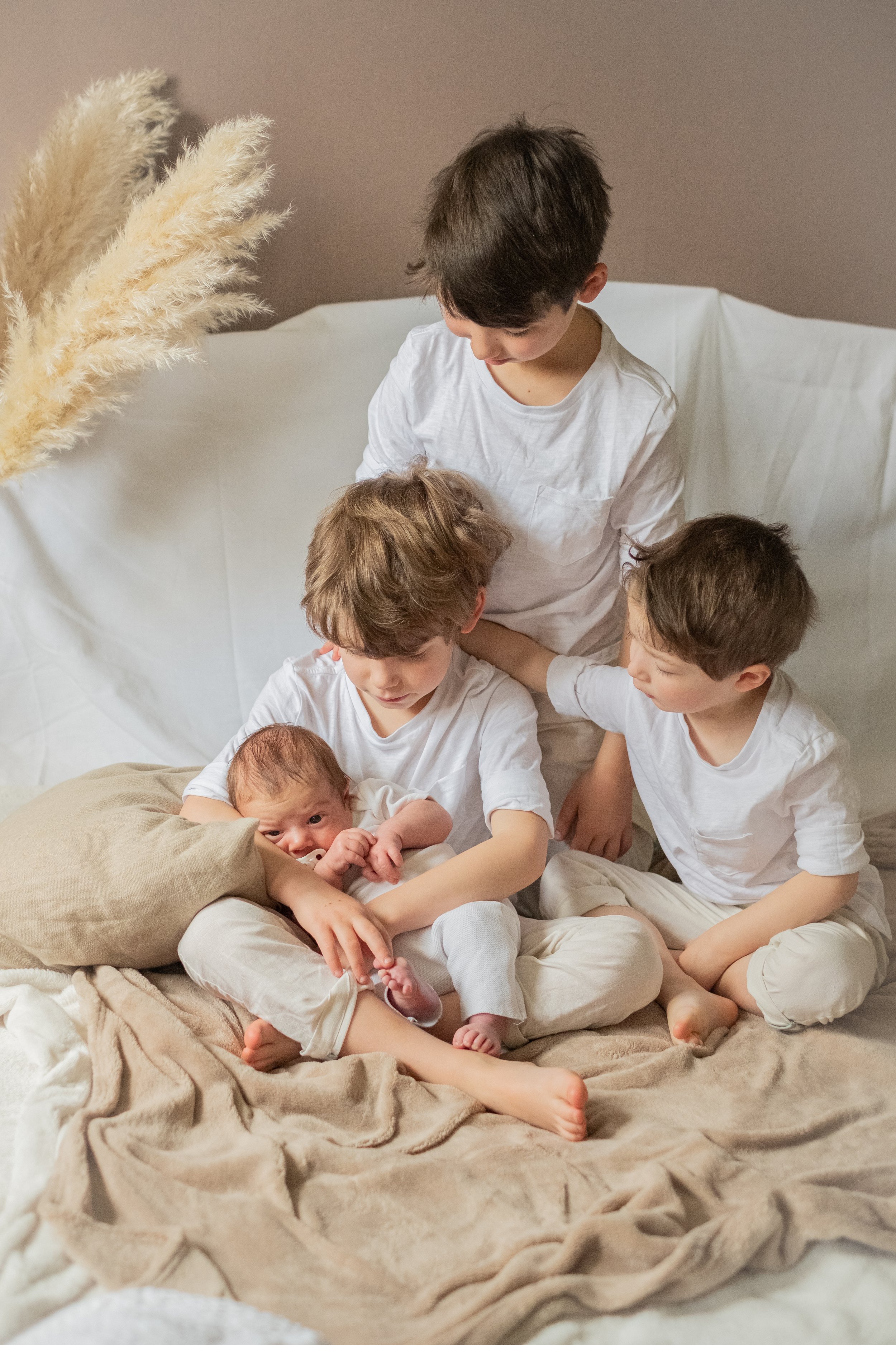 trois enfants assis sur le lit regardent leur nouveau petit frere