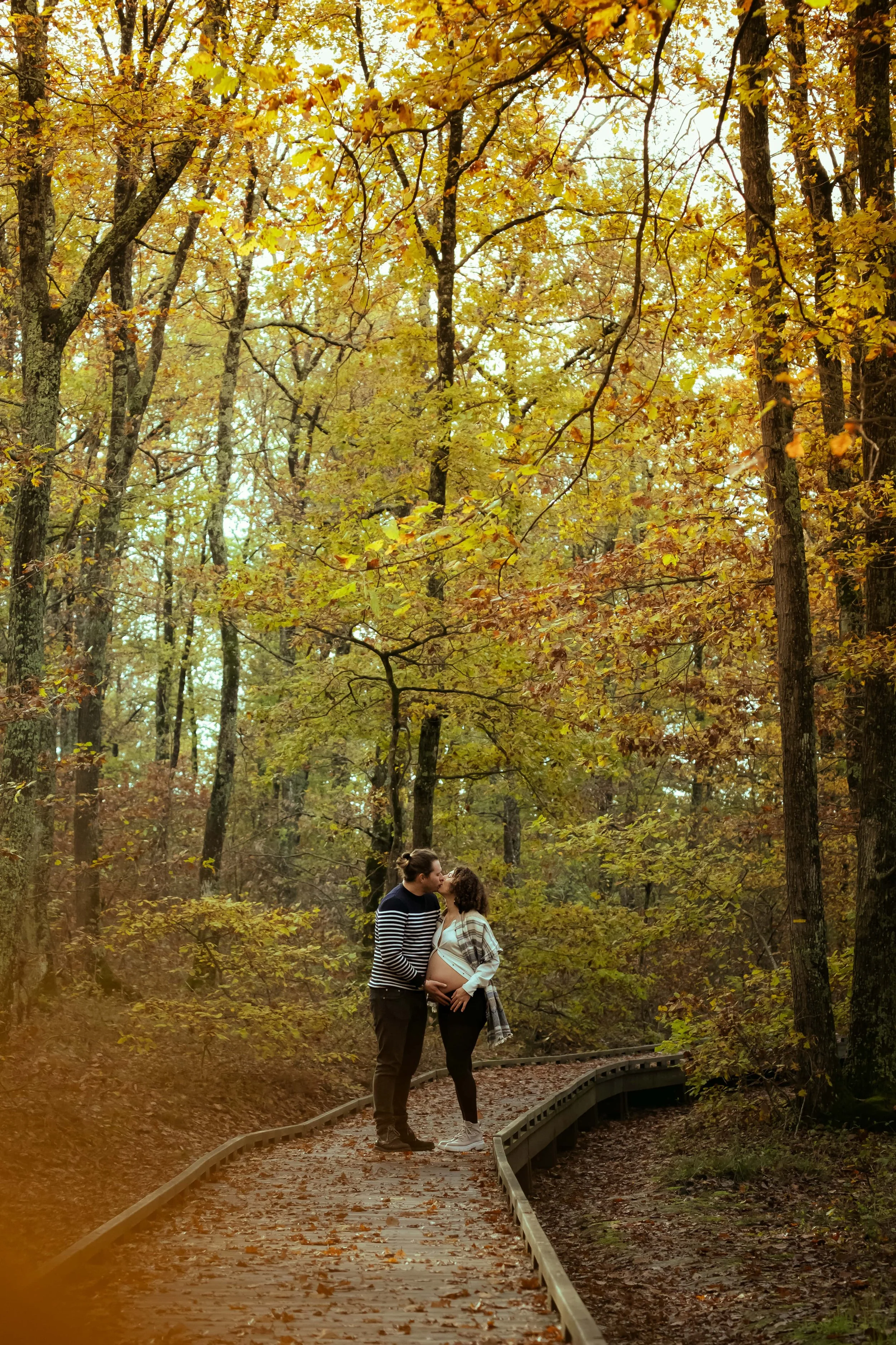 sur un chemin en foret un homme et sa femme enceinte s embrassent