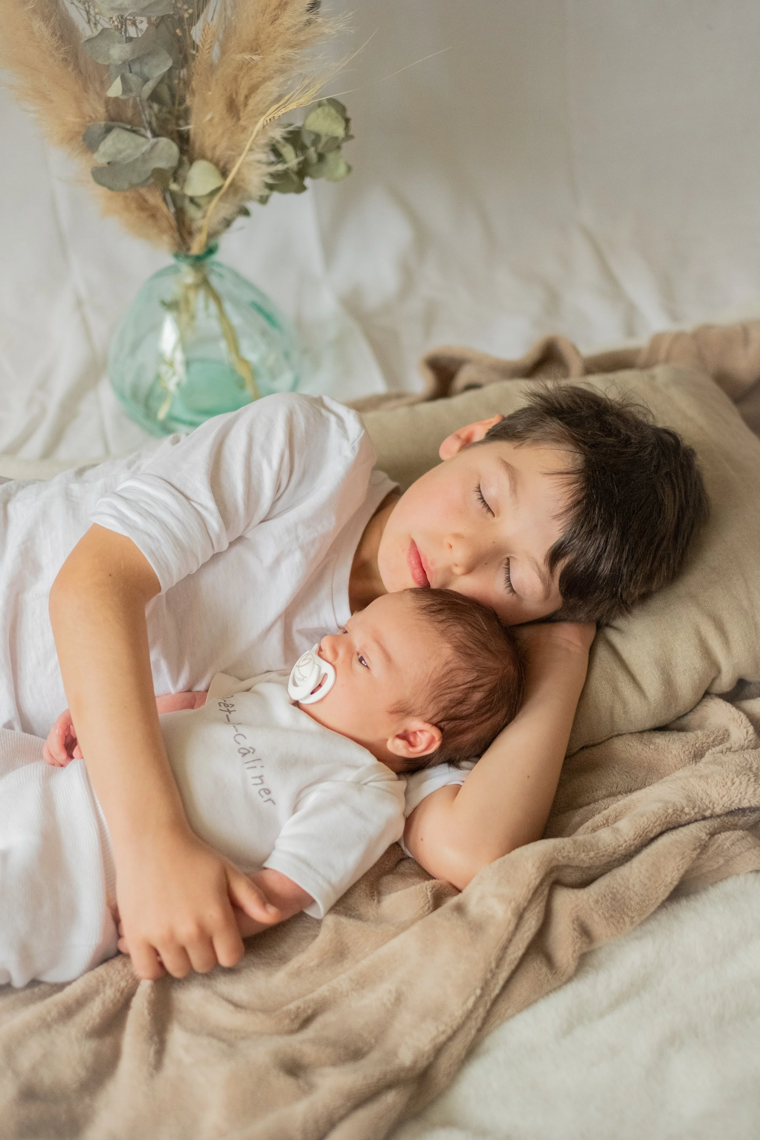 le grand frere prend son petit frere dans les bras ils sont allonges sur le lit