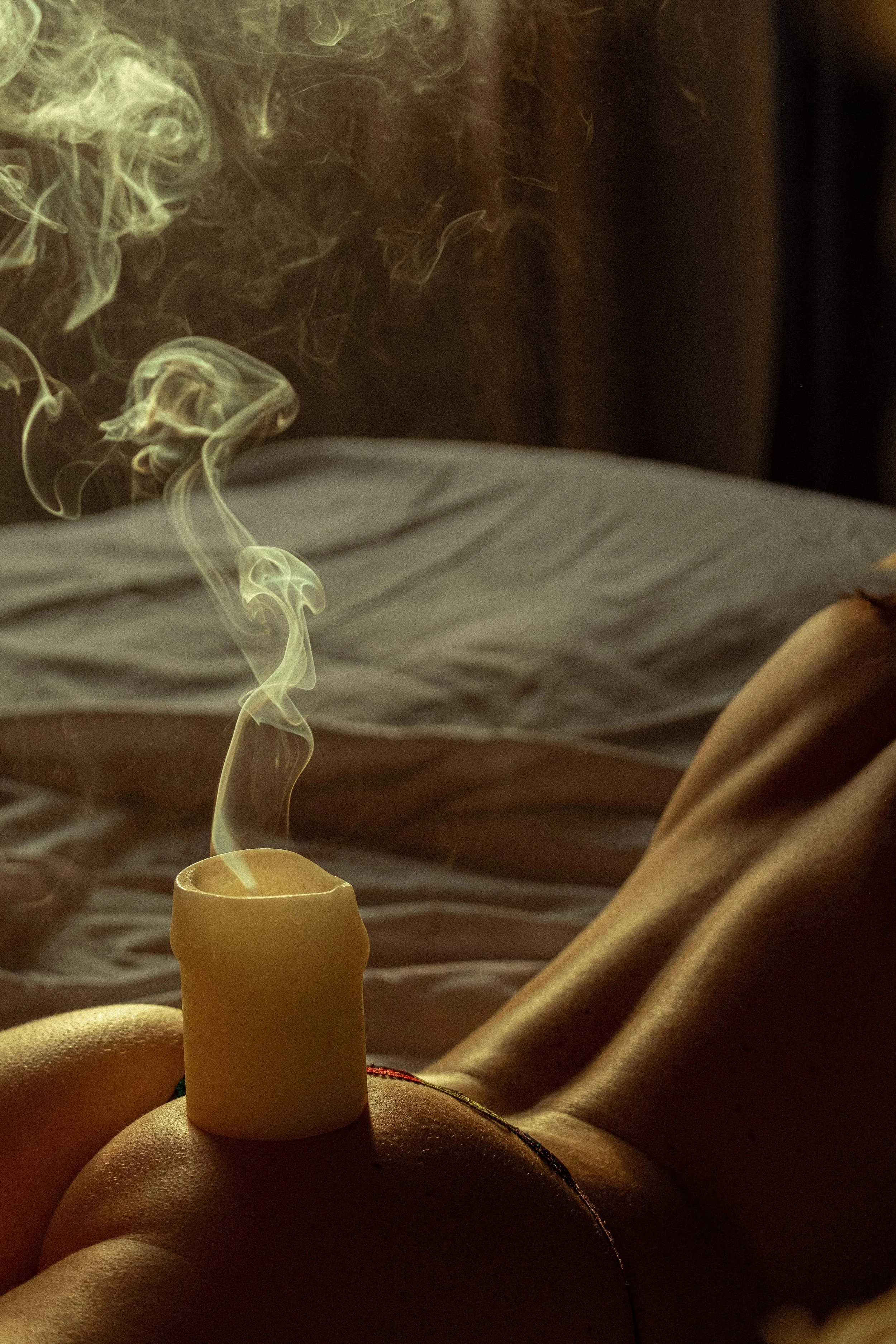fumee dune bougie sur le corps dune femme allonge au soleil sur un lit