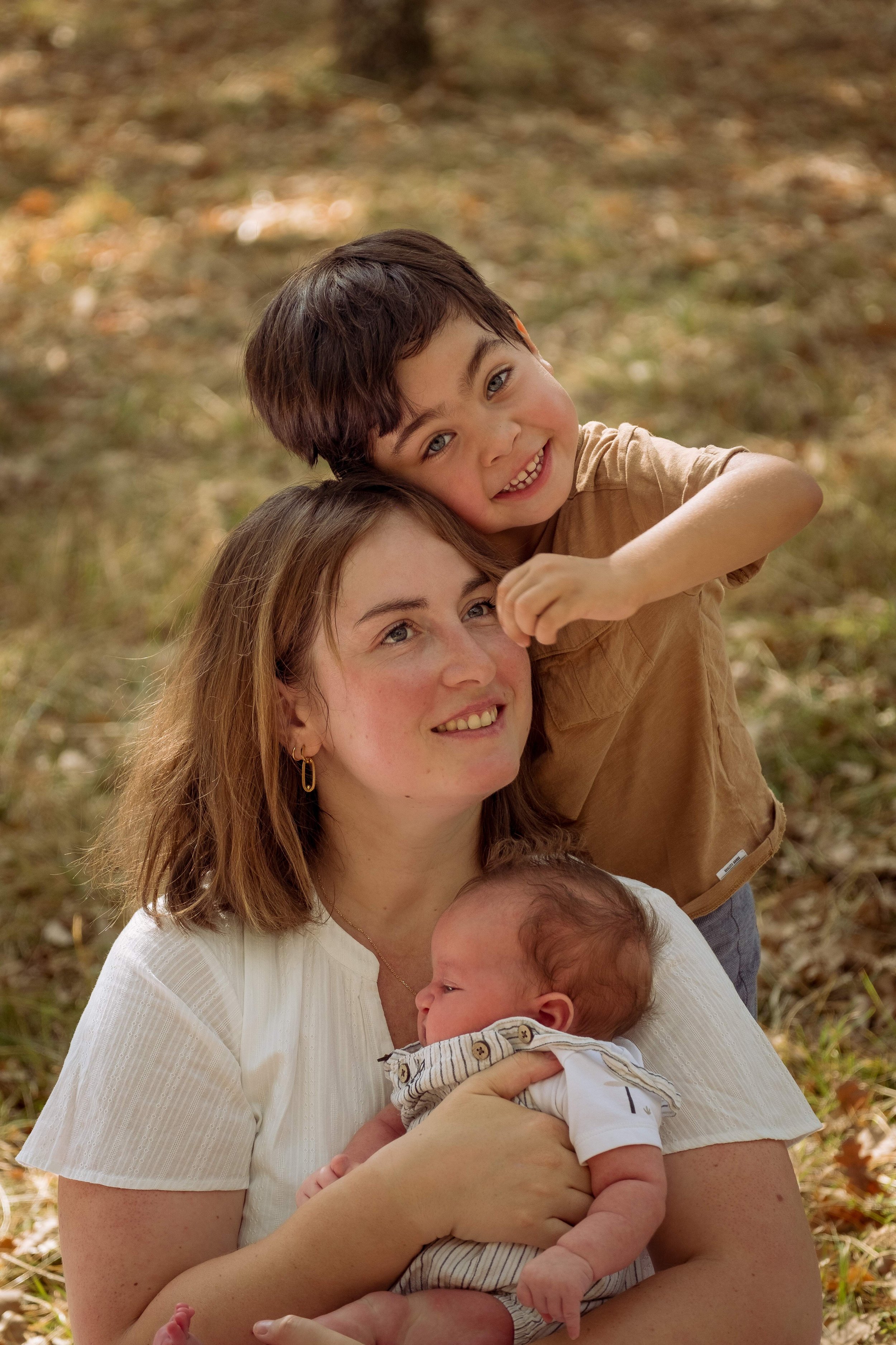 photo de la mere qui tient son bebe dans les bras avec son grand fils