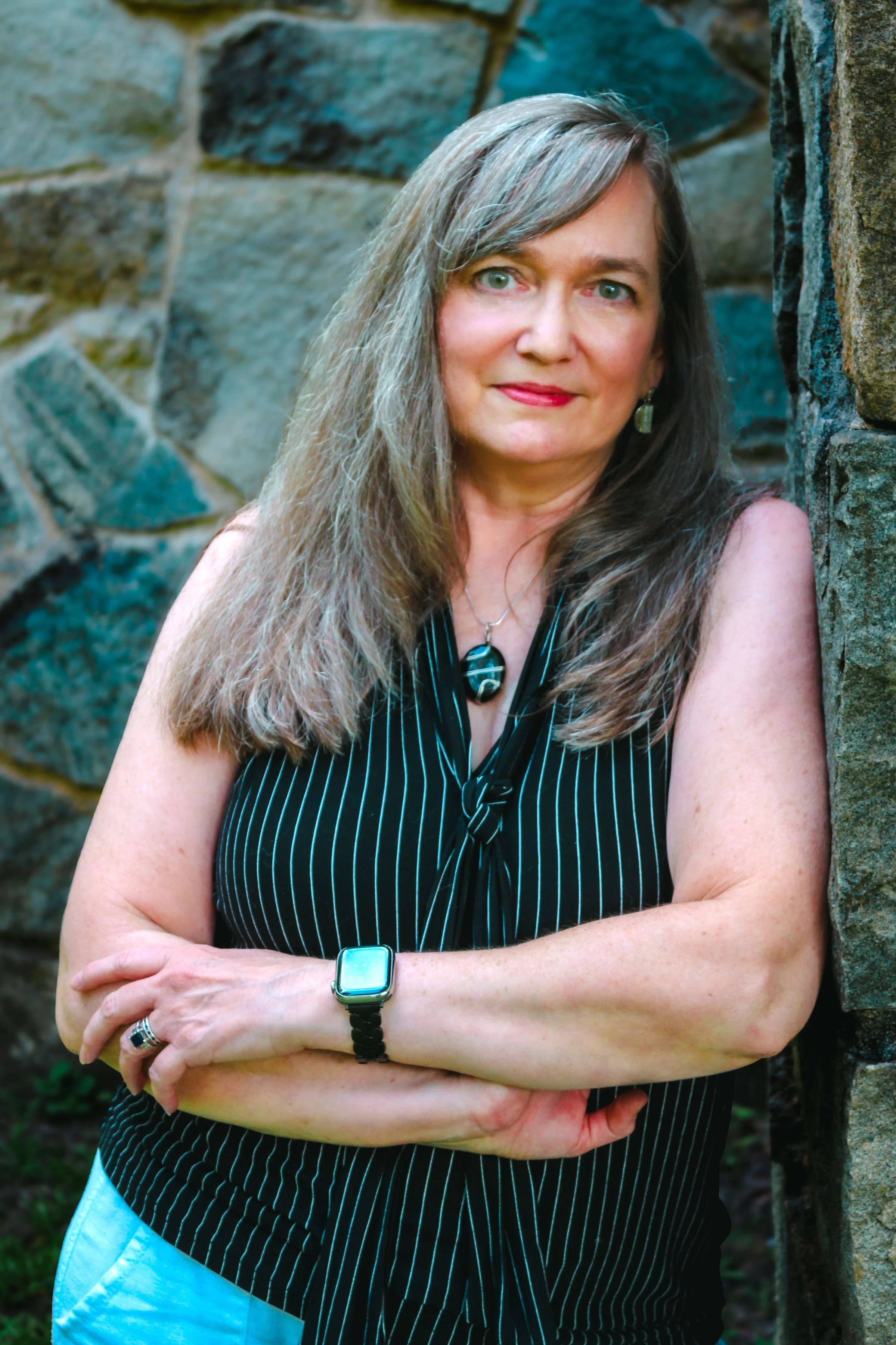 Beth Hovis, iridology instructor and holistic wellness educator, poses confidently against a stone wall, representing natural health education and business foundations for practitioners.
