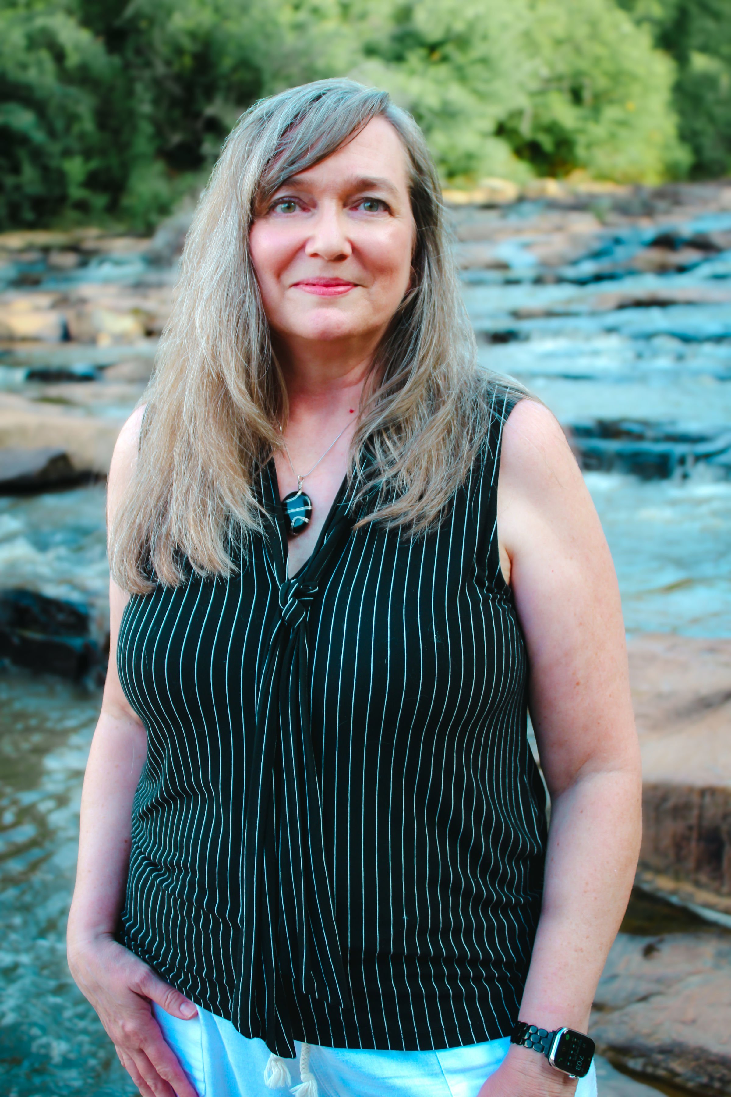 Beth Hovis standing in front of a river with rocks in the background.