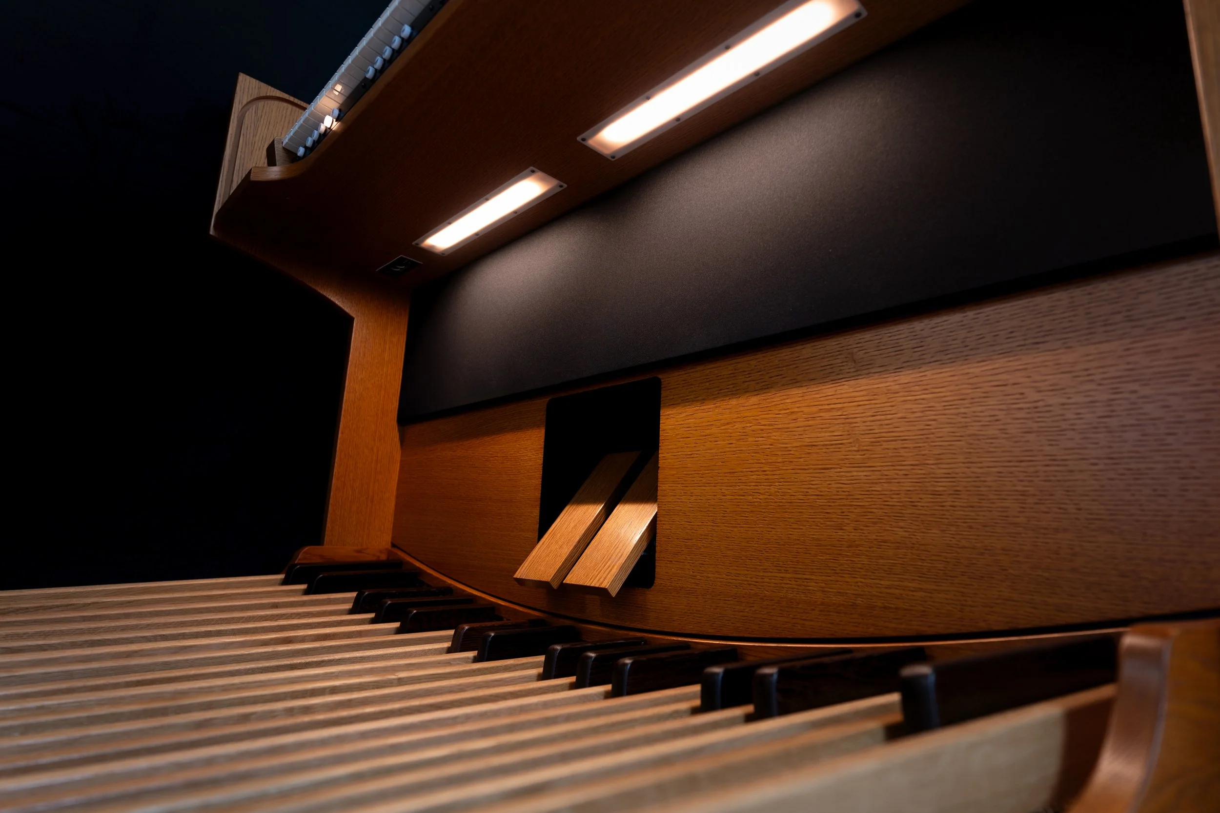 Close-up of a wooden upright piano with black and white keys, music stand, and built-in lighting