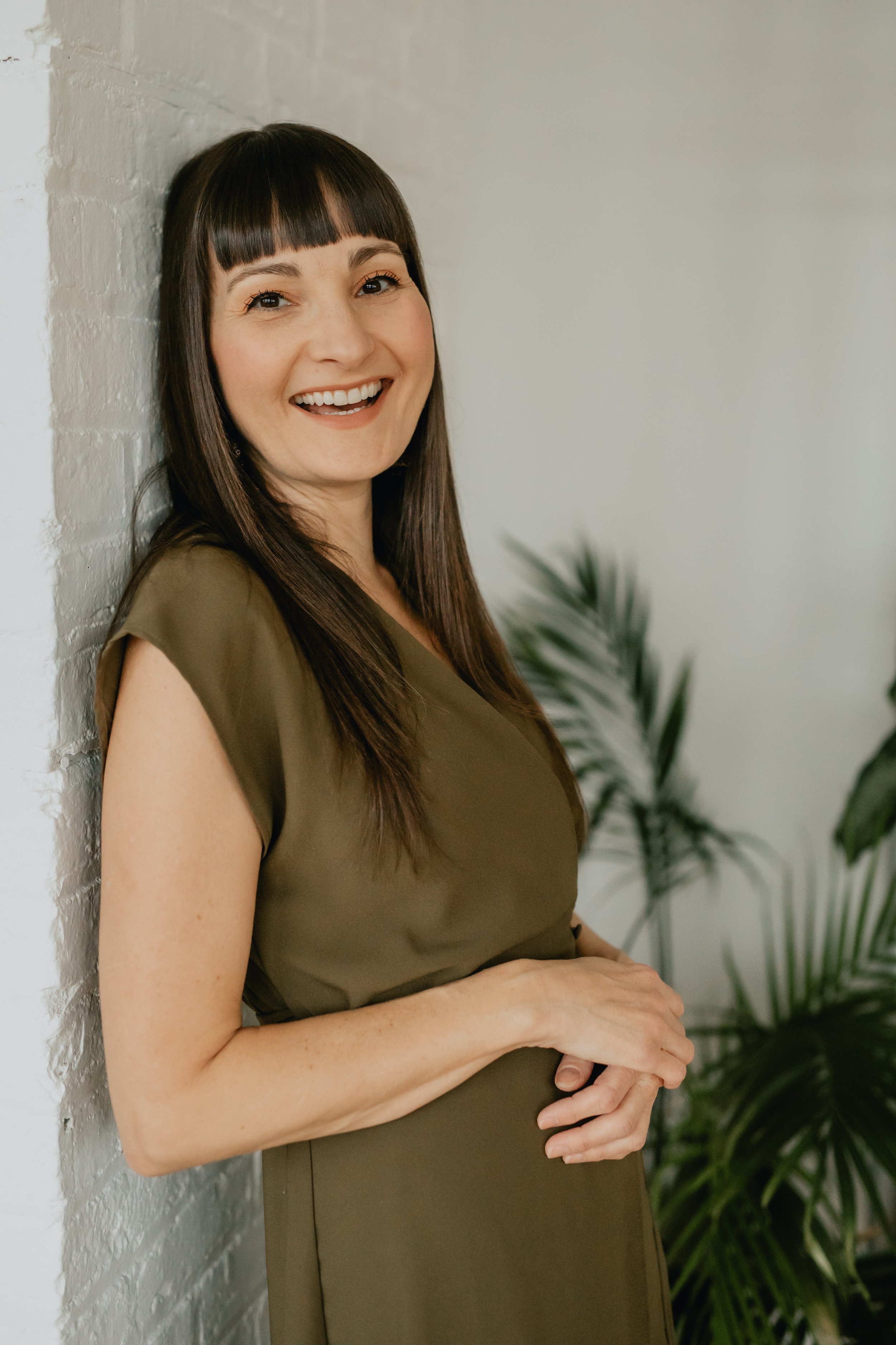 rachel mcgarry leaning against the wall smiling | &asanas hot yoga and pilates studio in london, ontario