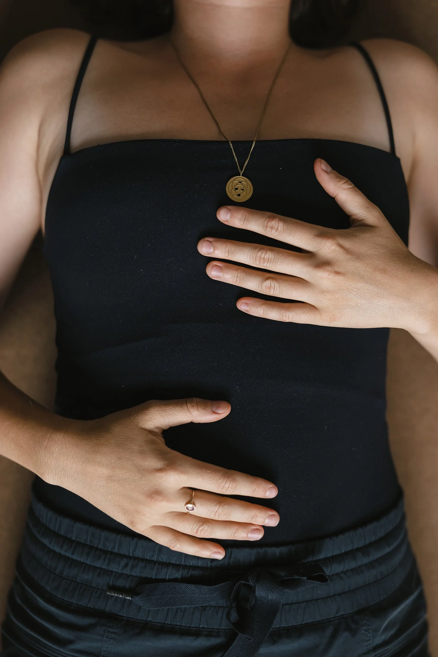 close up of a woman with her hands on her torso at a yoga class | &asanas hot yoga and pilates