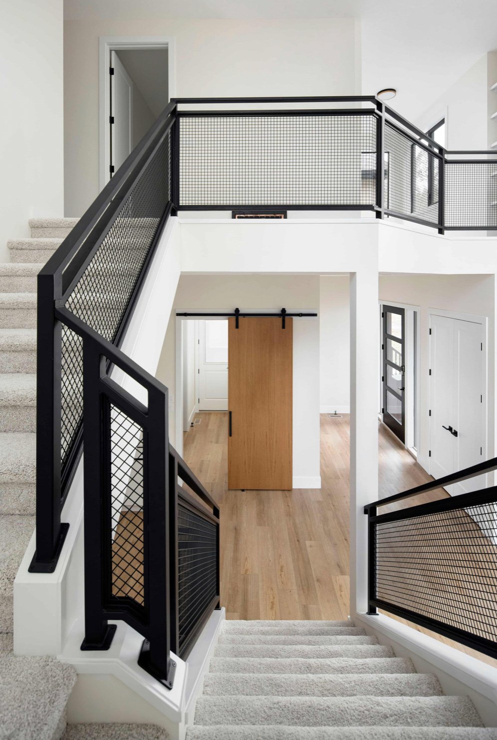a white staircase with black railings and a wooden door