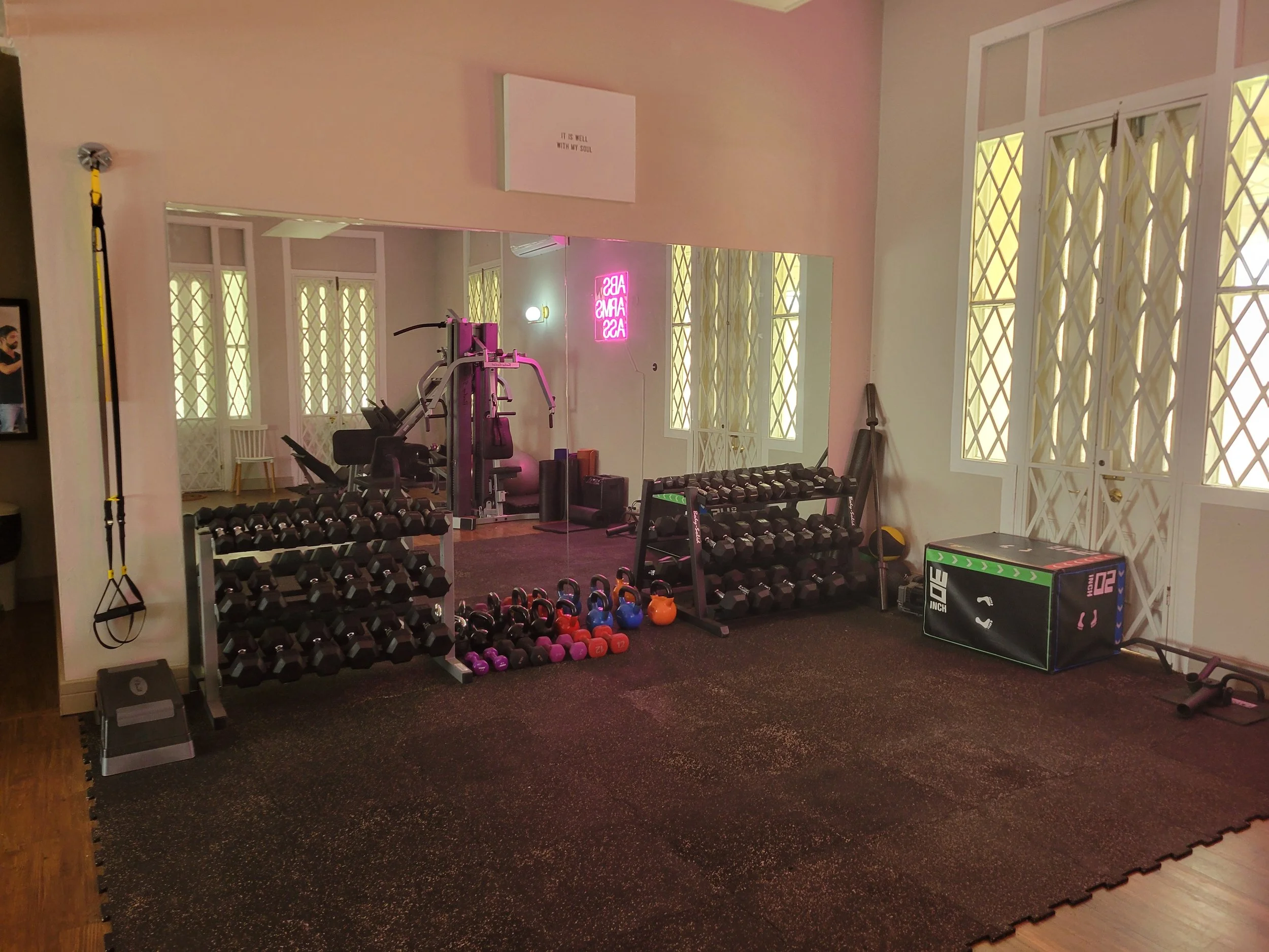Home gym with dumbbells, kettlebells, resistance bands, a plyometric box, and a mirror on the wall
