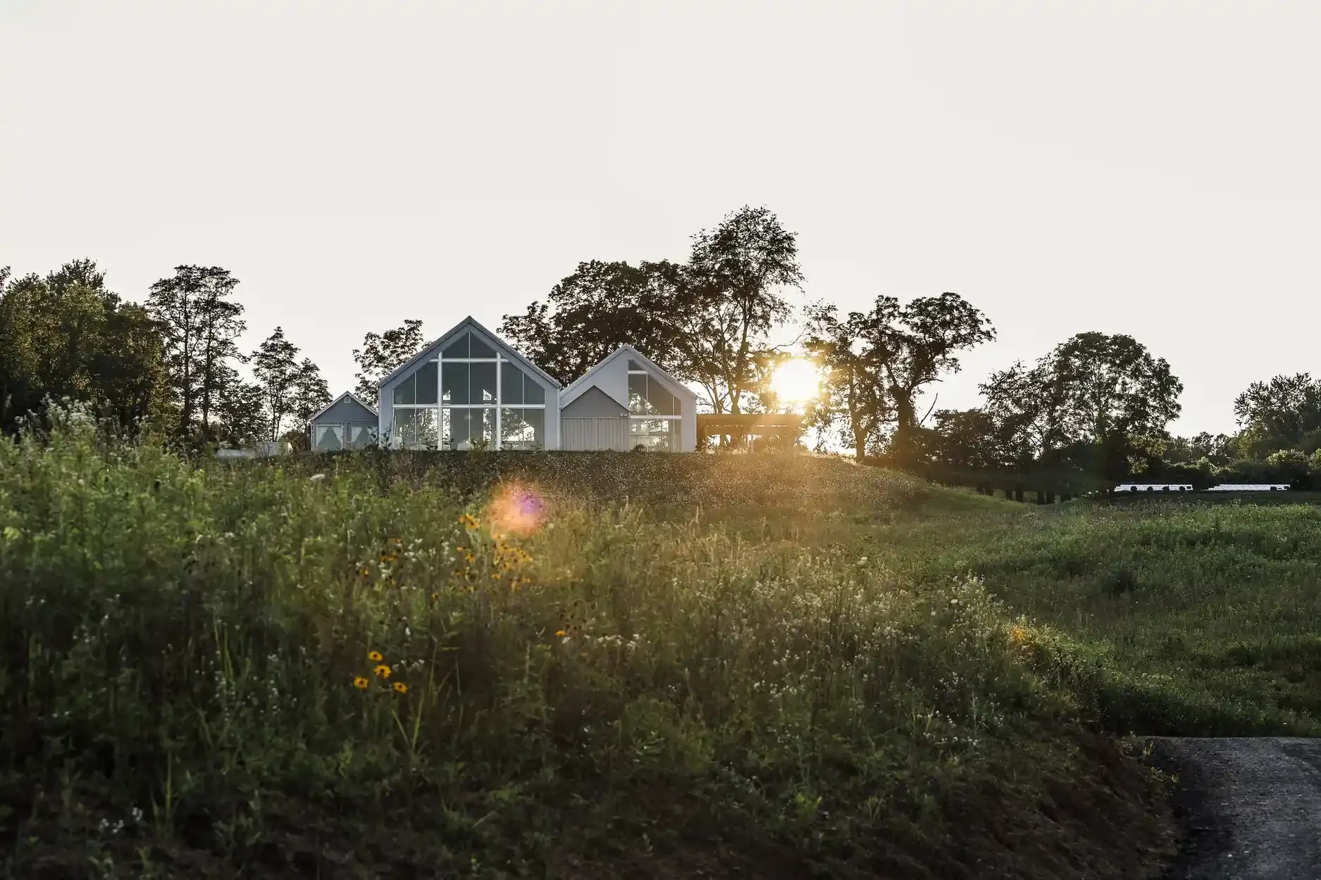 Modern glass A-frame event venue at golden hour surrounded by wildflower fields in Hocking Hills Ohio