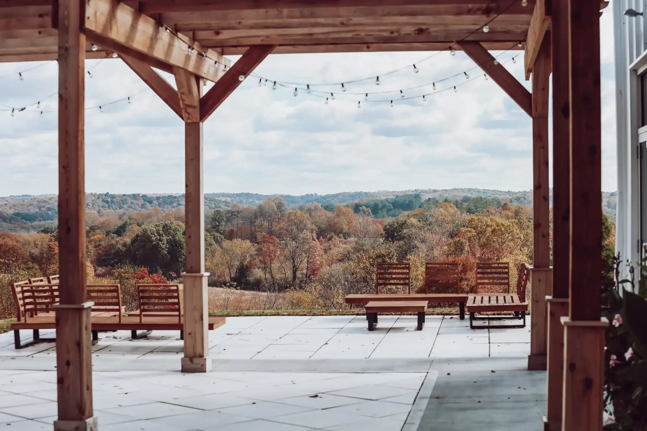Covered pergola patio with string lights overlooking fall foliage at The Seventy Five Hocking Hills