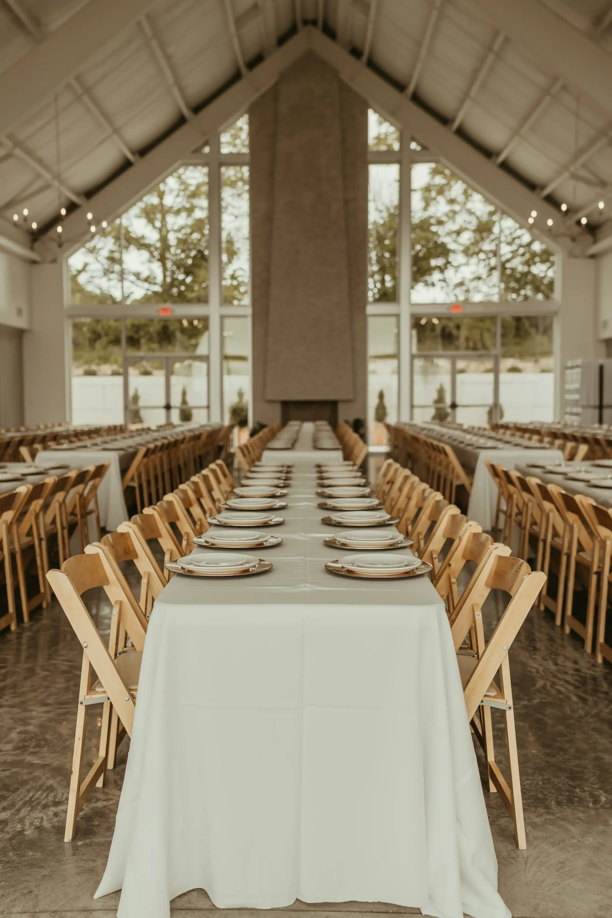 Bright banquet hall with long white-linen tables and vaulted cathedral windows set for corporate event