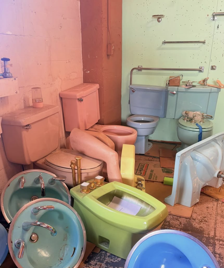 Display of vintage toilets and sinks in pastel colors arranged on the floor in a novelty bathroom decor setting.