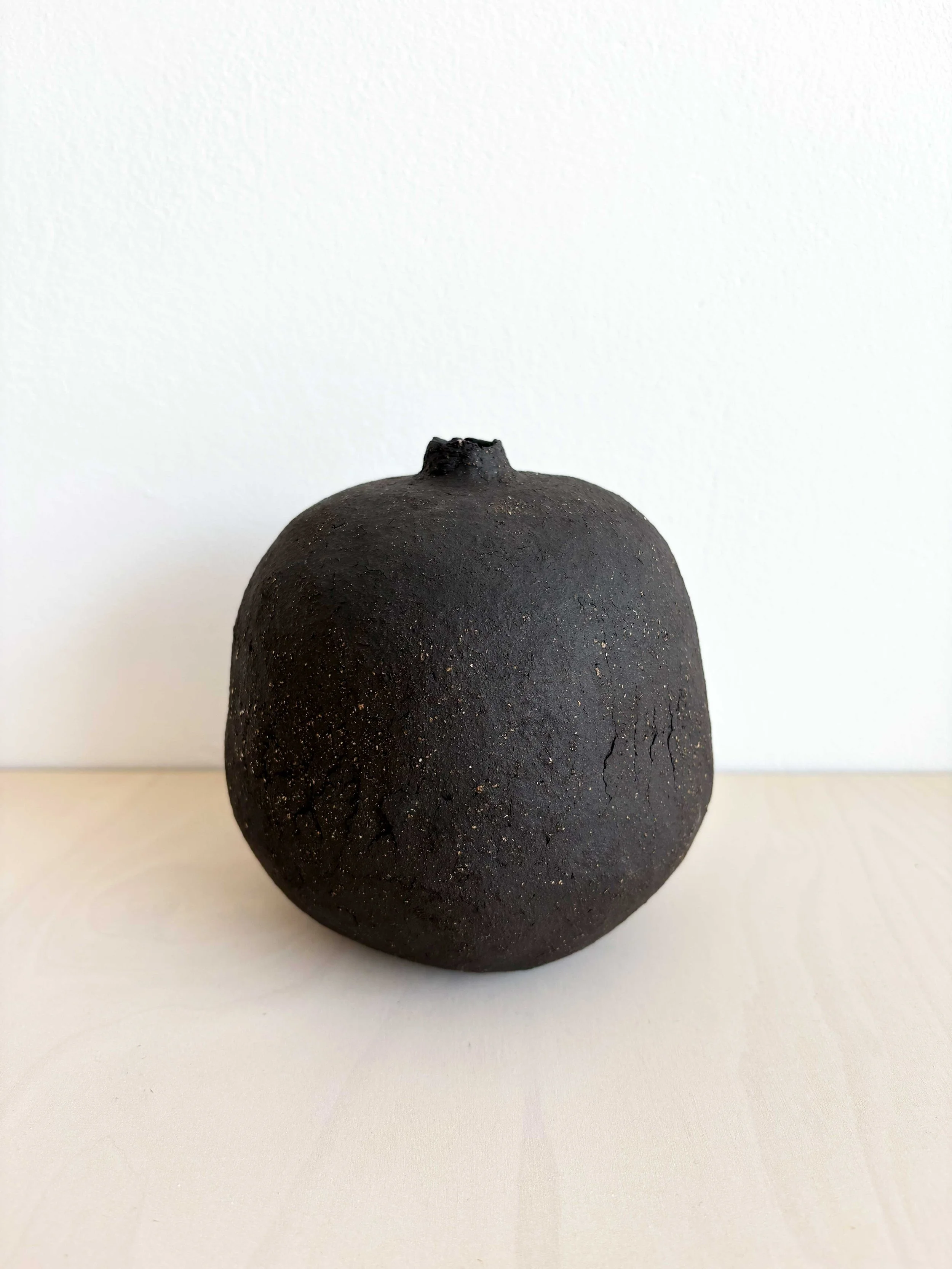 Schwarz matte, rundliche Keramikvase auf weißem Hintergrund