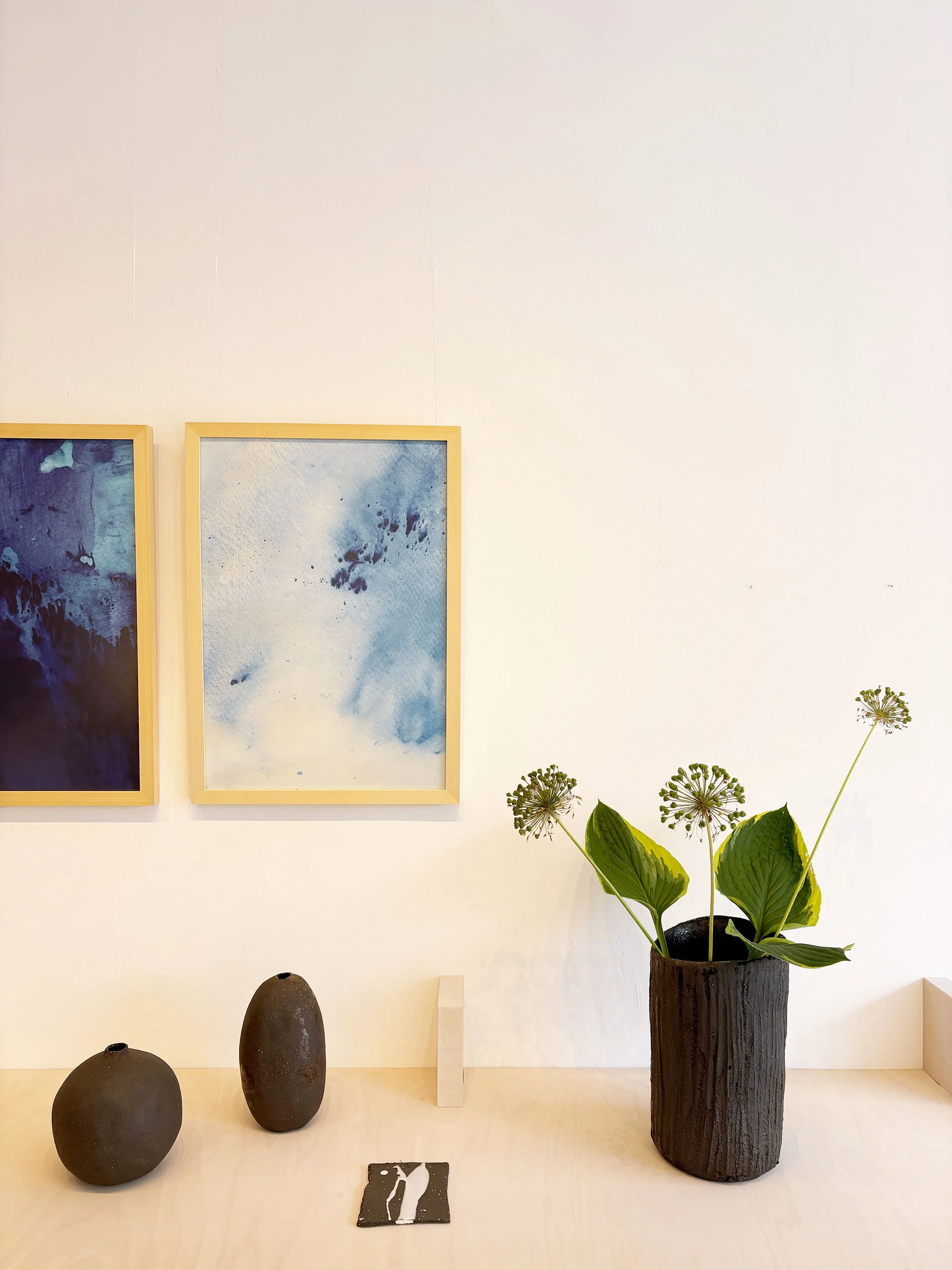 abstrakt blaue Kunstdrucke und schwarze Keramikvasen im Ladengeschäft
