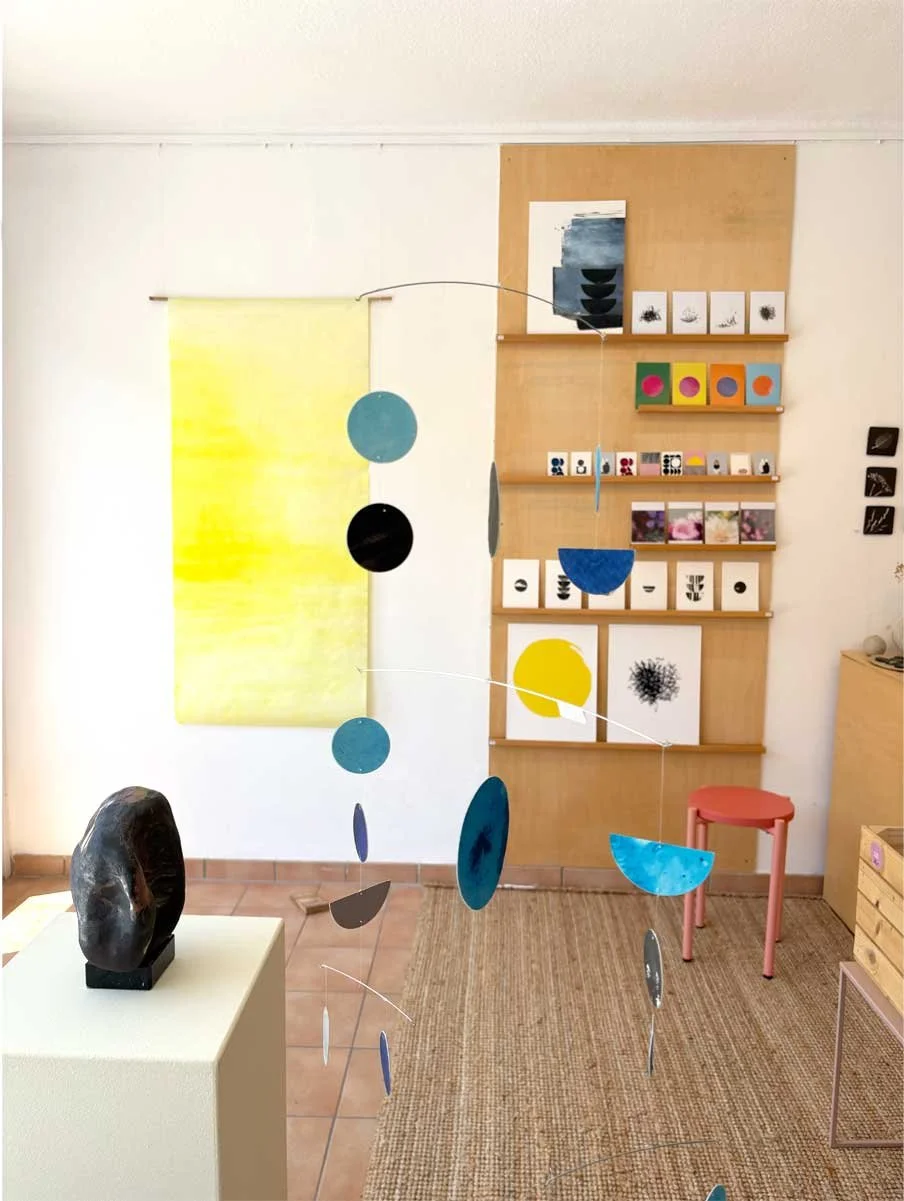 Ladenansicht Galerieraum mit Mobile, gelbem Wandbild und verschiedenen Drucken